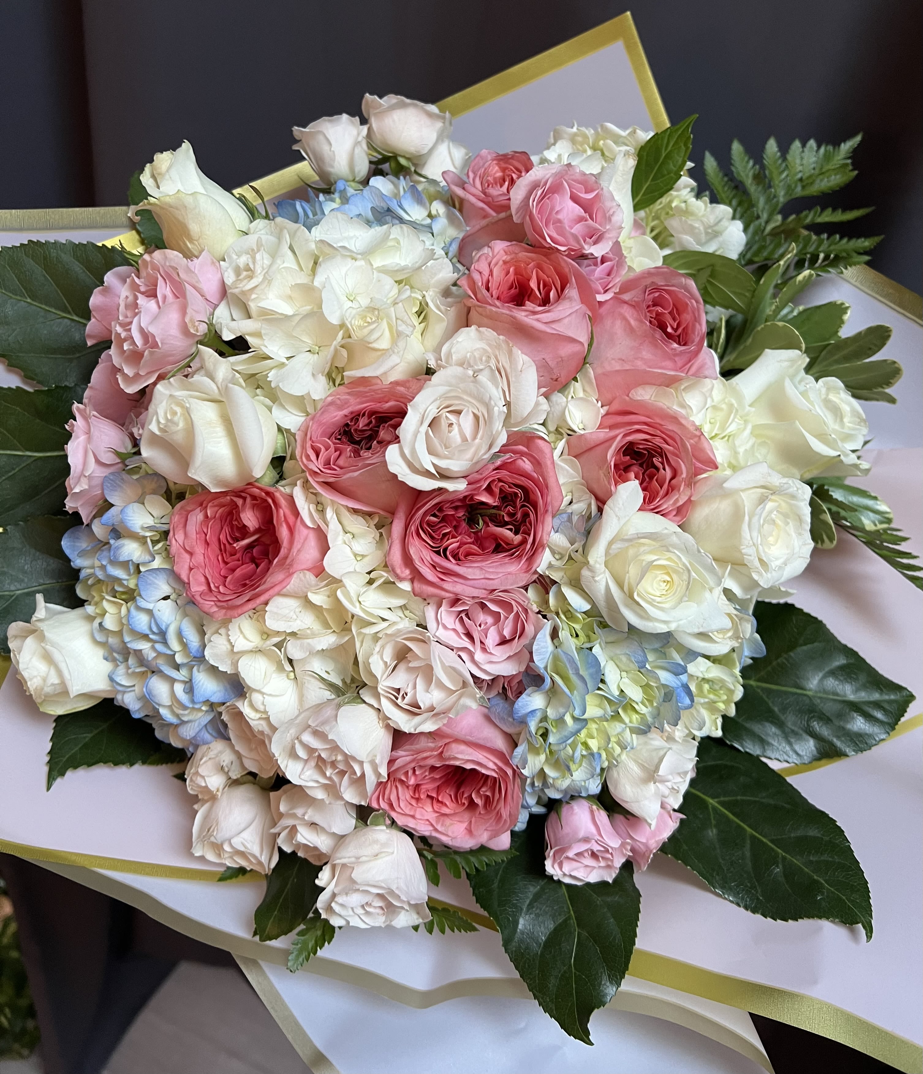 Luxury Hues Wrapped Bouquet  - European style grand bouquet of exquisite pink garden roses, delicate ivory and blush spray roses, elegant white roses, stunning light blue and white hydrangeas accentuated by lush greenery and hand arranged in a luxury pink wrapping paper with a golden trim. Water bubble is attached to the bottom of the stems to keep blooms fresh and hydrated during transportation. This arrangement is a perfect choice for birthdays and special occasions as well as for proposals, grand romantic gestures, surprises and anniversaries. This unique large bouquet will definitely make a statement and leave a recipient speechless.