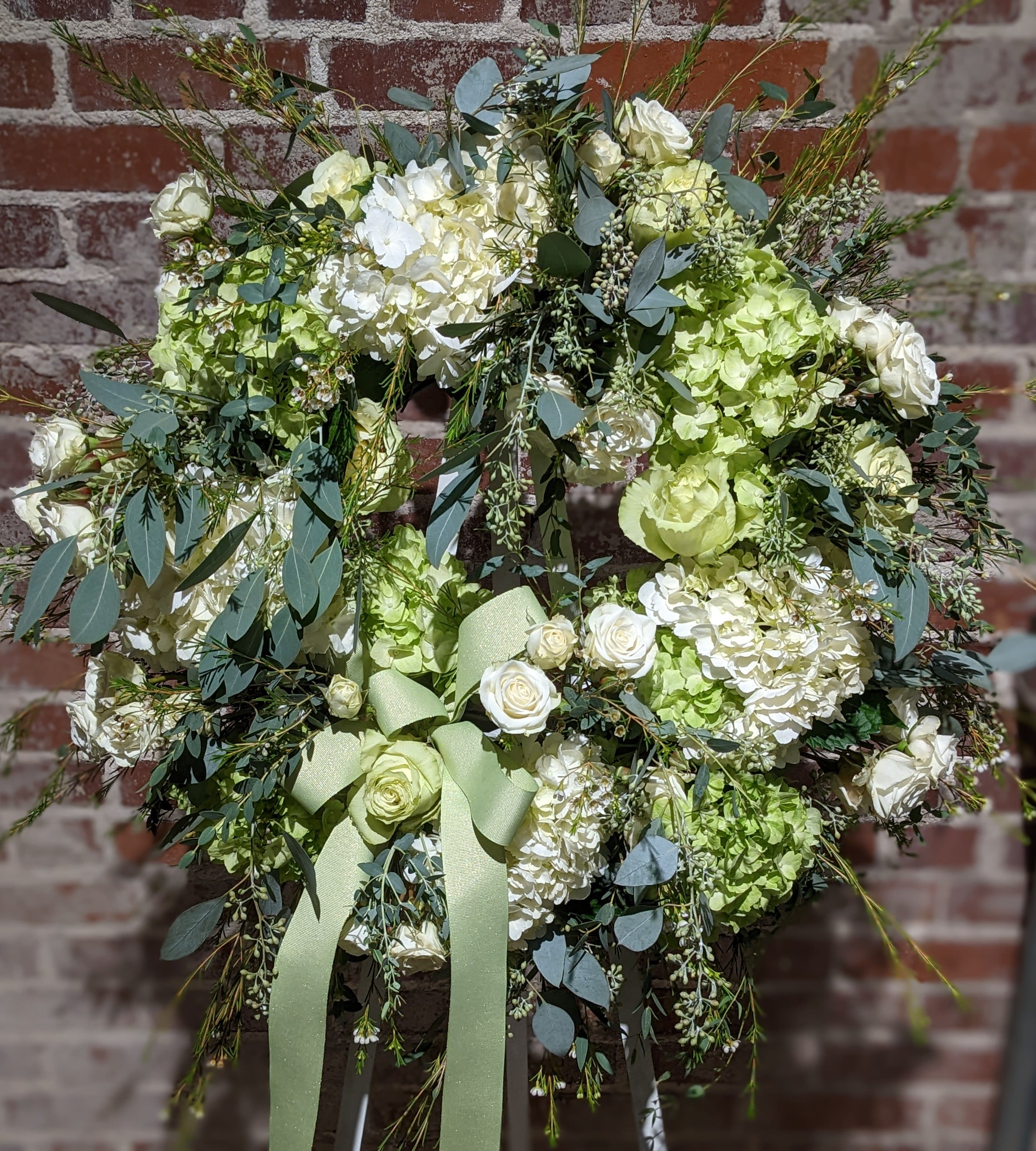 Limelight Memorial Wreath Limelight Memorial Wreath - A beautiful floral tribute for the deceased. A lush palette of soft green and white blossoms accented with assorted foliages create a sophisticated statement for this celebration of life. Additional color palettes are available upon request. 48 hours notice is required for a color substitution. Please call the shop at 404-314-6194 to discuss.