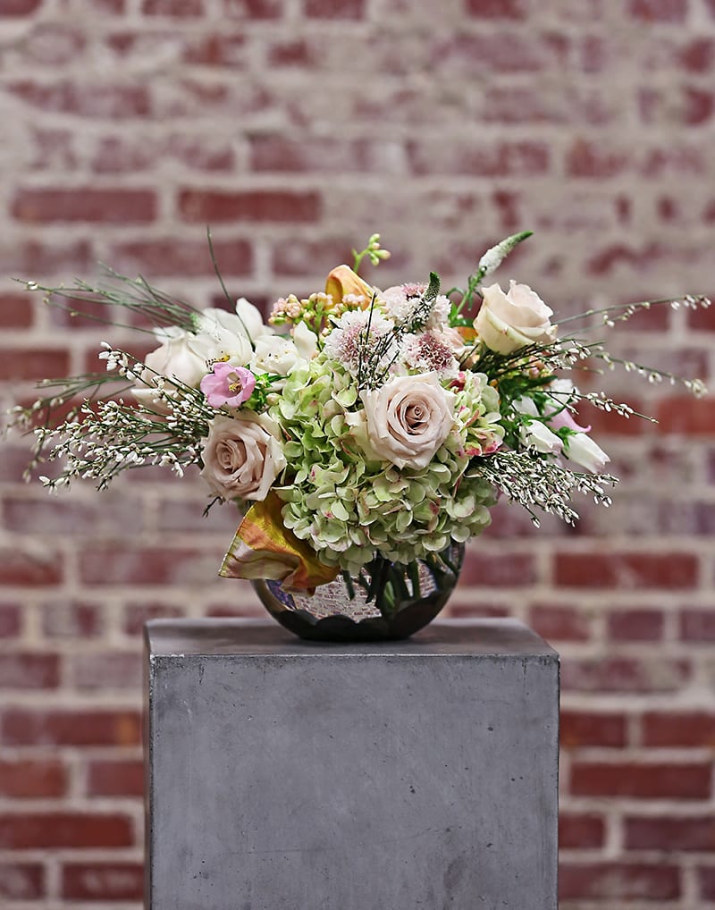 Toujour Paris - The perfect way to say, &quot;Bonjour&quot;!  A lovely romantic composition of classic flowers in subtle hues and varied textures. A rich silk ribbon woven into the arrangement seals the deal. Presented in a clear glass bubble bowl with exposed stems.