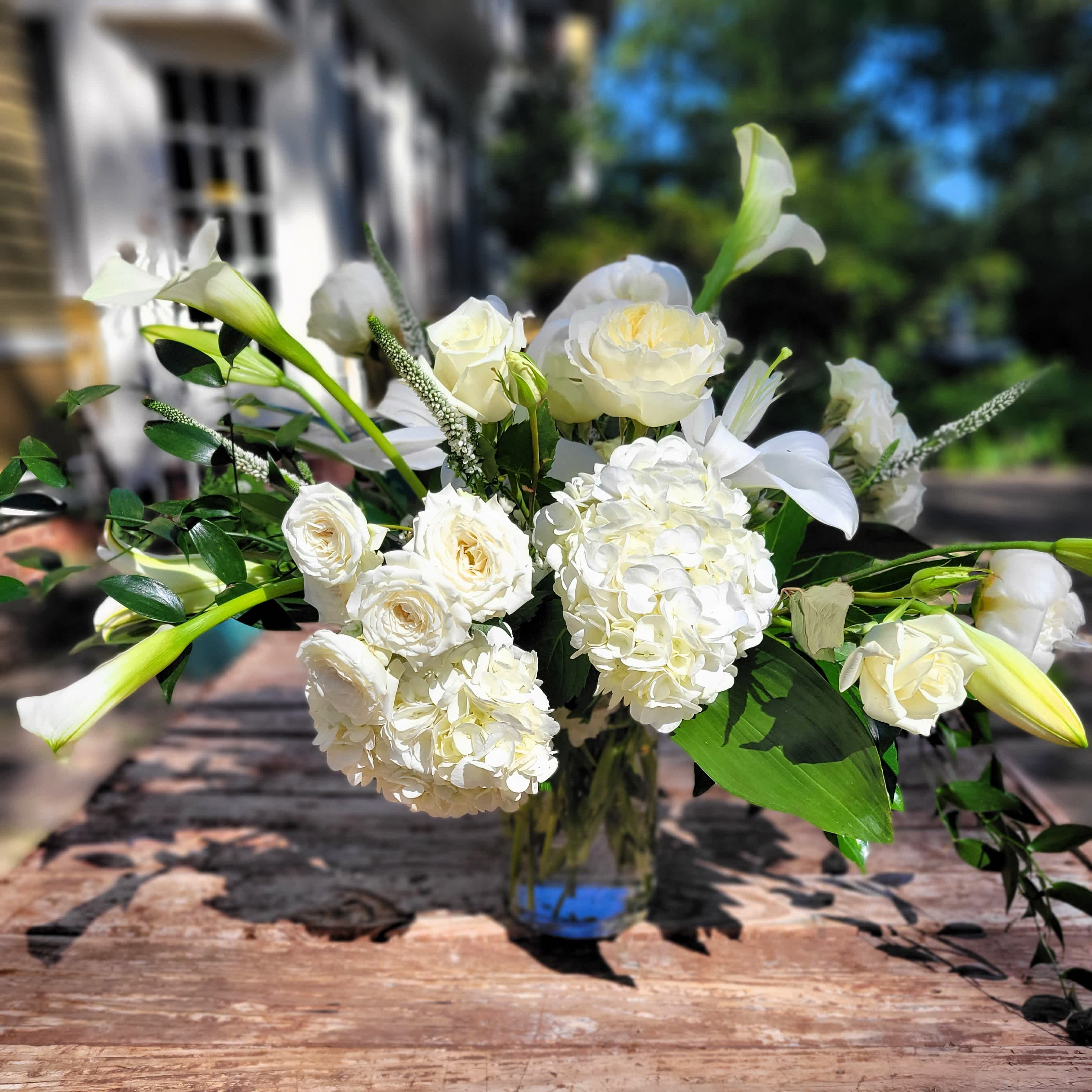 Tranquility - Experience a peaceful tranquility.  A wonderful combination of statement foliages along with green and white flowers in a variety of textures. Presented in a clear container. Stems concealed with submerged foliage.
