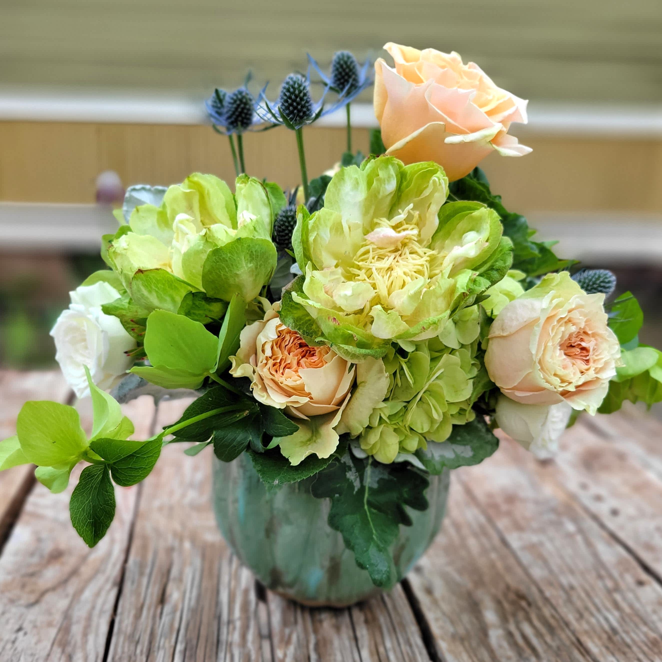 Victoria - Soft expression in pastel shades. Premium mixture of imported product for South America. Hydrangea, garden &amp; spray roses, hellebore, thistle and assorted foliage. Designed in a reusable green glazed ceramic cachepot. 