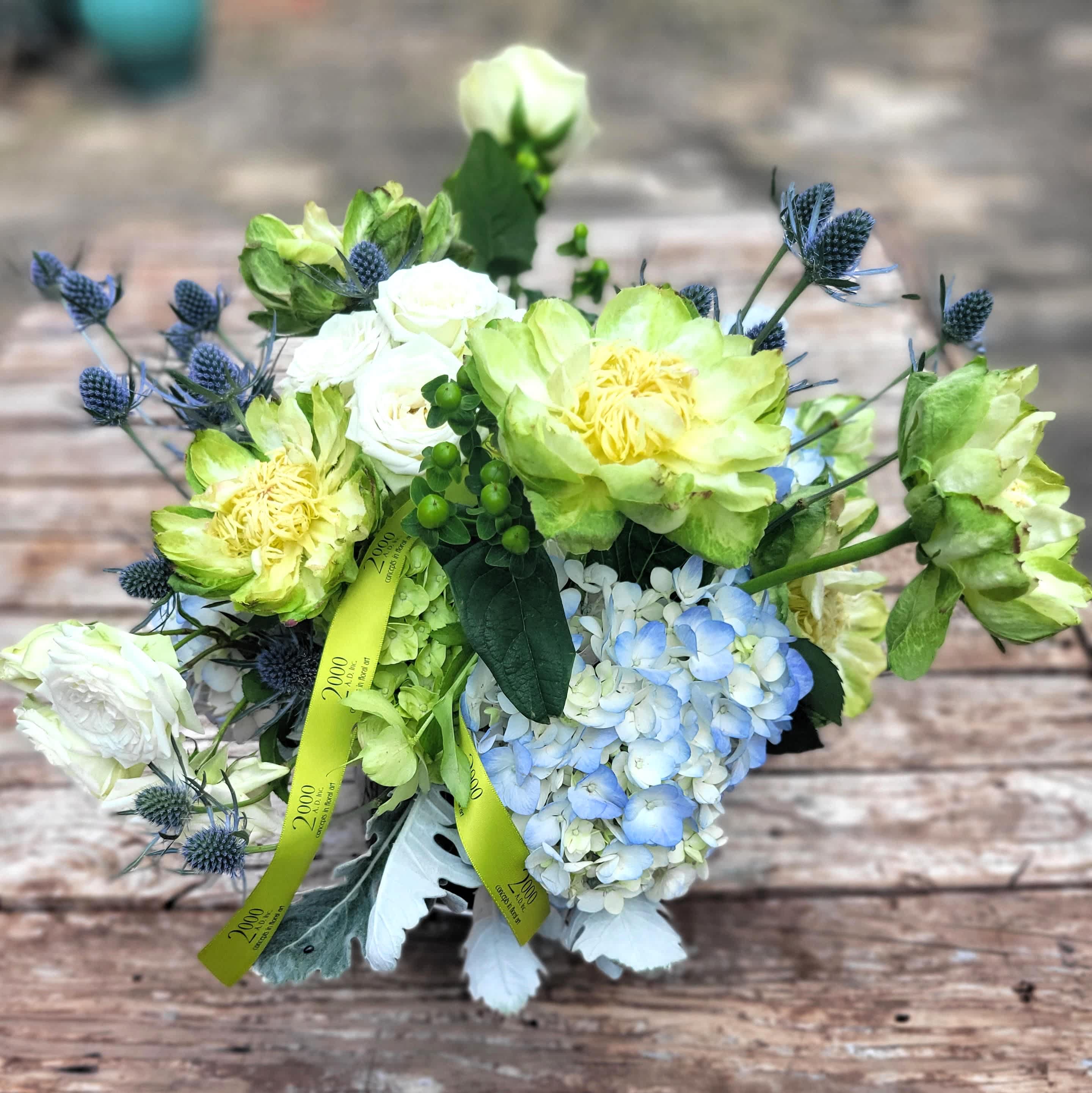 Arielle - Lush composition in soothing hues of blues, greens and whites. Designed in a clear glass cube with exposed stems.