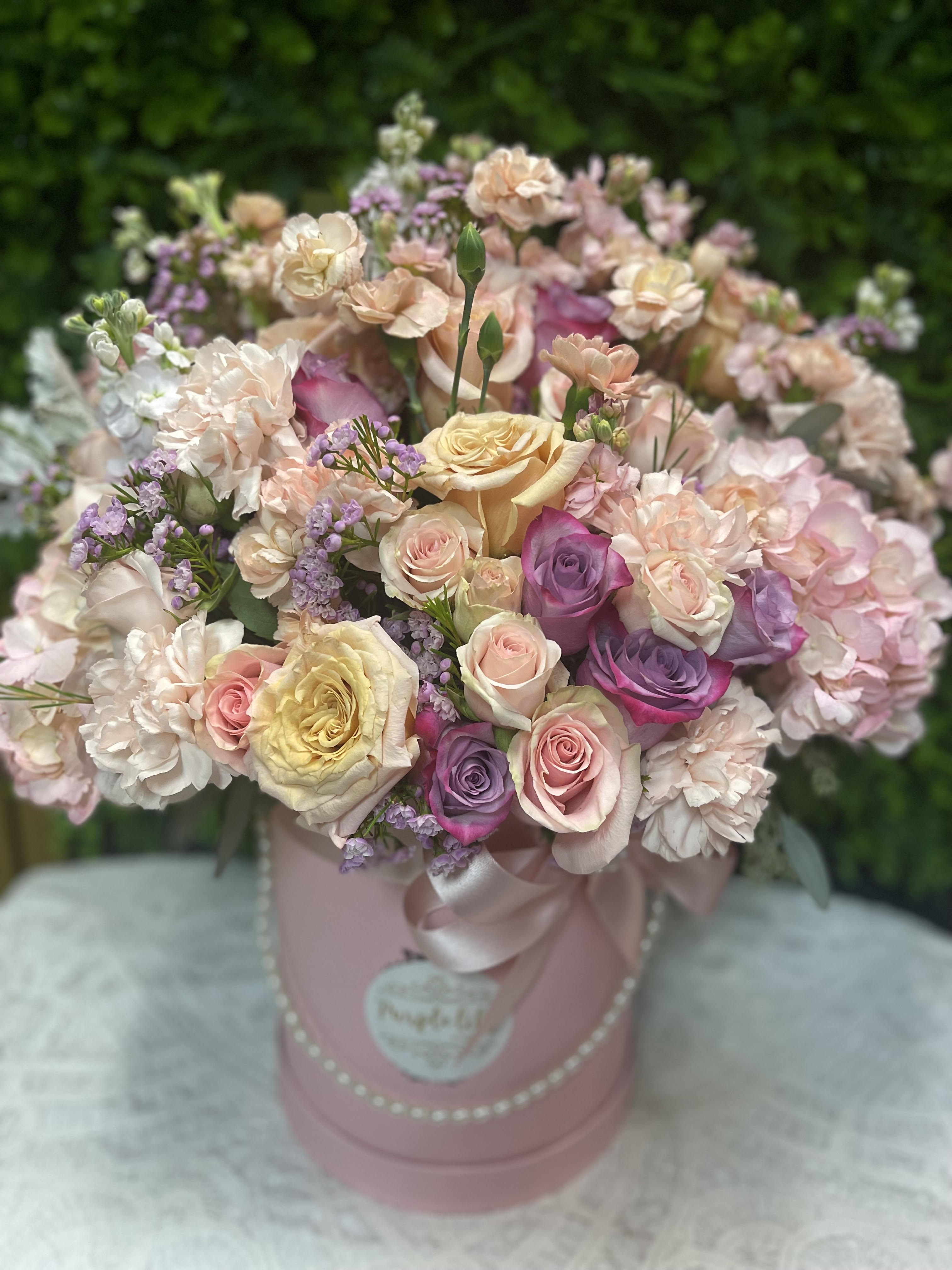 A Soft Whisper PLA28 - Light pink hydrangea, pink roses, lavender spray roses, tulips and stock arranged in a white cylinder box.