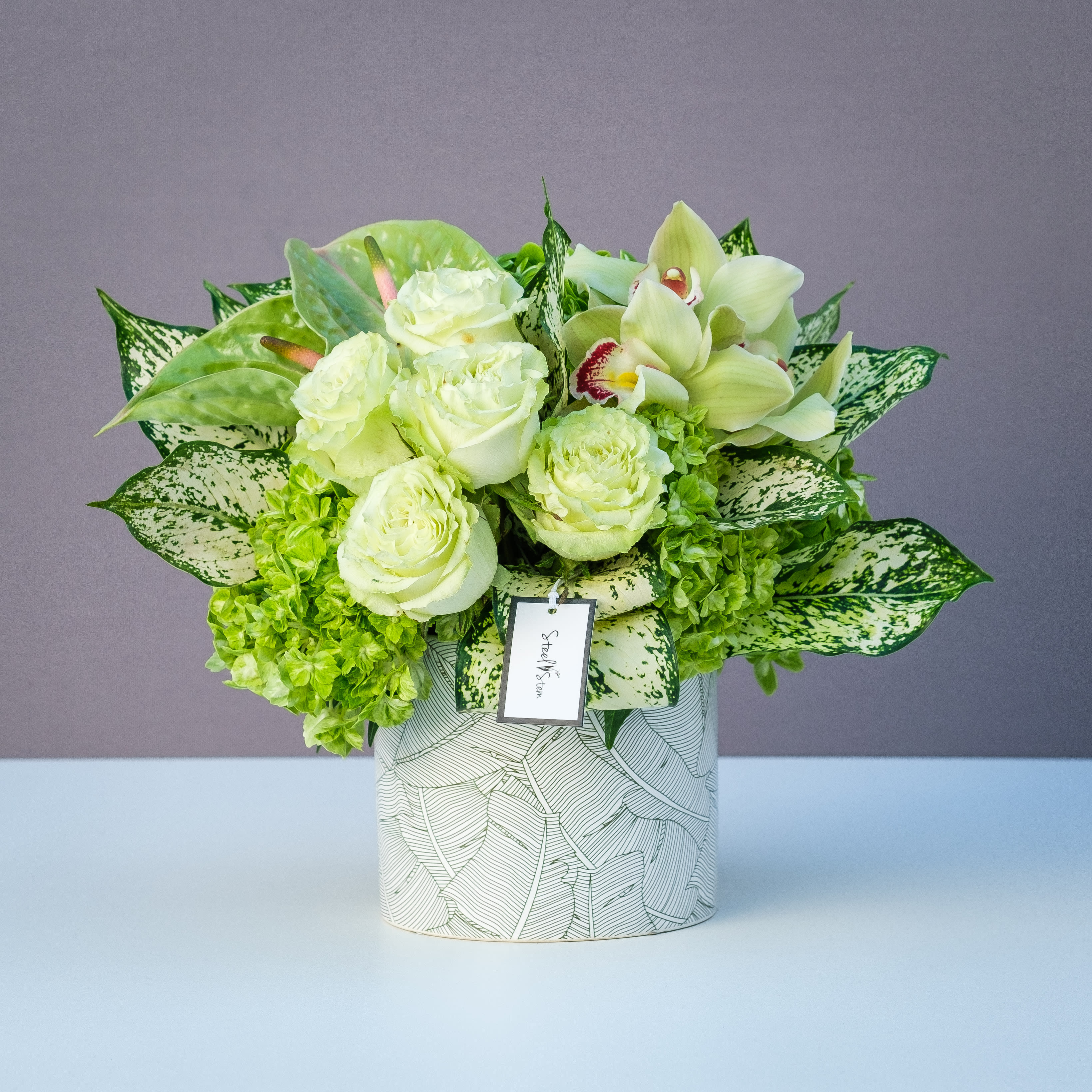 Forever Green Forever Green - A monochromatic green and chic arrangement of green roses, emerald green hydrangea, tropical anthuriums and orchids and complimented with premium variegated leaves that is hand-designed inside of a leaf-imprinted ceramic vase.