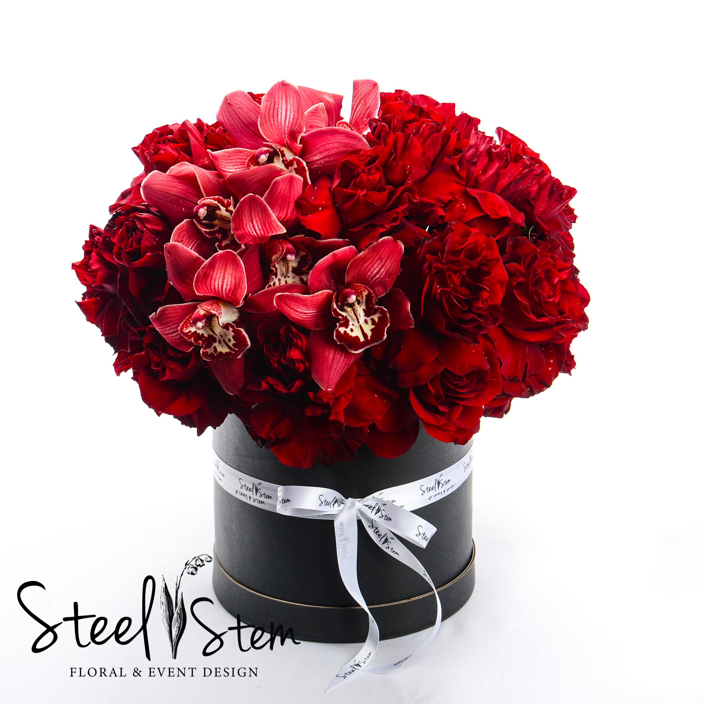 Love Love - Two dozen red roses and burgundy cymbidium in a matte box with our signature Steel Stem ribbon is the perfect gift for Valentine's Day, Anniversary or just to show your love to your special one.Please note that roses are open by hand for this specific design. Choose this gift to send your love in the most romantic way possible and really treat that special someone to a luxury gift they'll never forget! This box is reusable and can be easily be repurposed for home decor. Approximately 10"L x 10"W x 10"D.