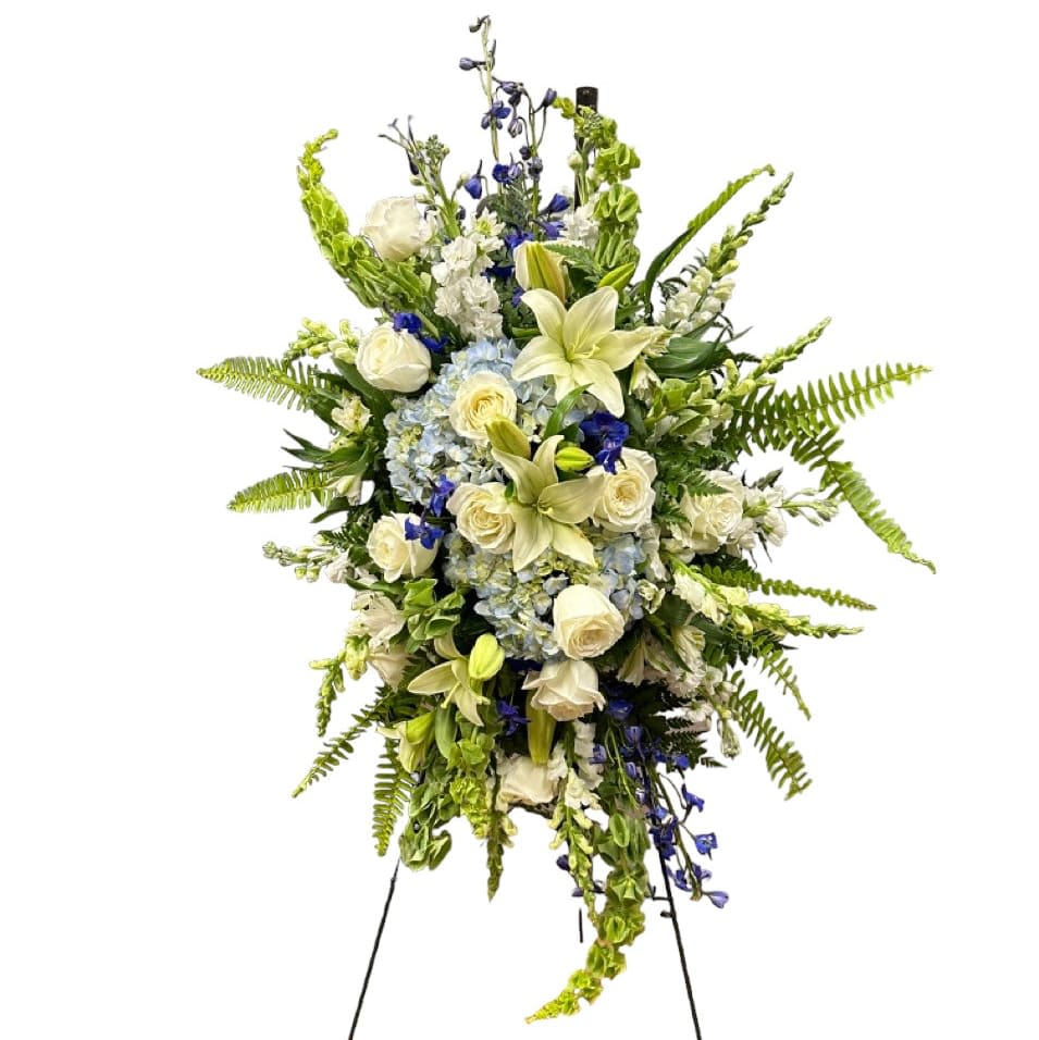 Tranquil Serenity Tranquil Serenity - Tranquil Memories: Blue & White Farewell Tribute is a beautiful arrangement designed to honor cherished memories. It includes blue hydrangeas, white lilies, blue delphiniums, lush greens, and white roses. These flowers symbolize gratitude, purity, depth of emotion, and eternal love. Together, they create a serene and heartfelt tribute, offering comfort and peace during a time of grief