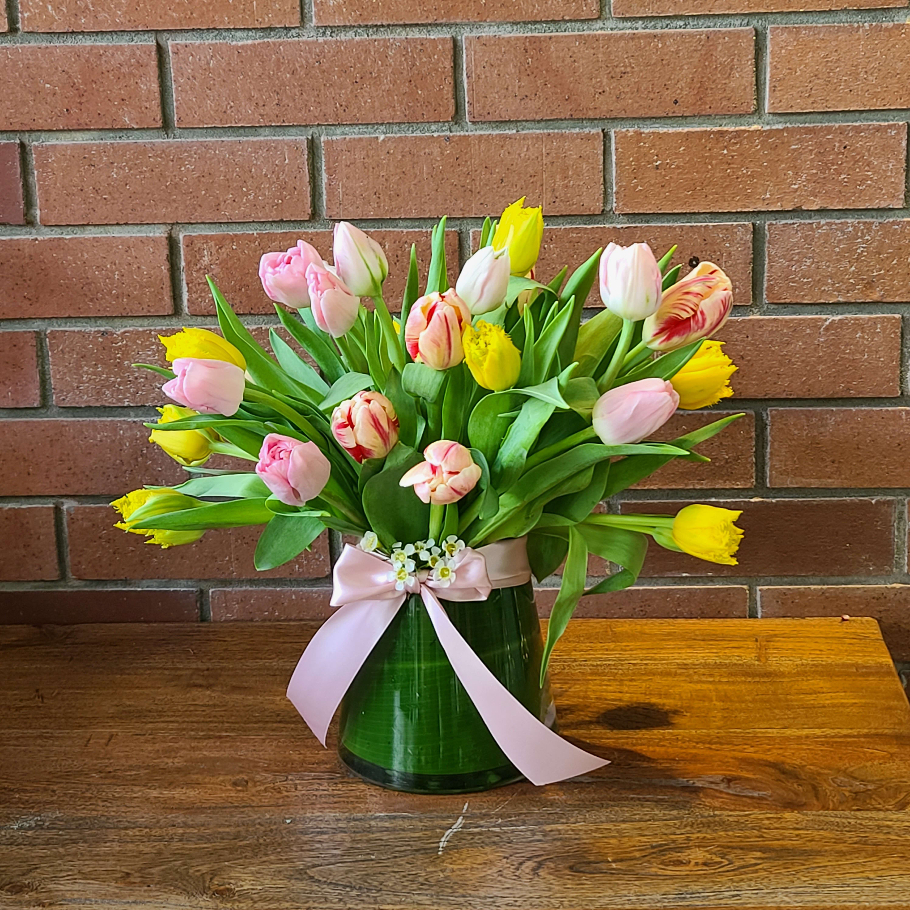 25 Spring Pastel Tulips  - 25 Spring pastel tulips from Holland in a modern pyramid vase decorated with a green leaf and  high quality soft double satin ribbon bow. Some of the Holland tulips are double blooming tulips and others look variegated. Tulips reflect the light so they might be delivered open to the recipient. The colors of tulips may vary based on daily availability 