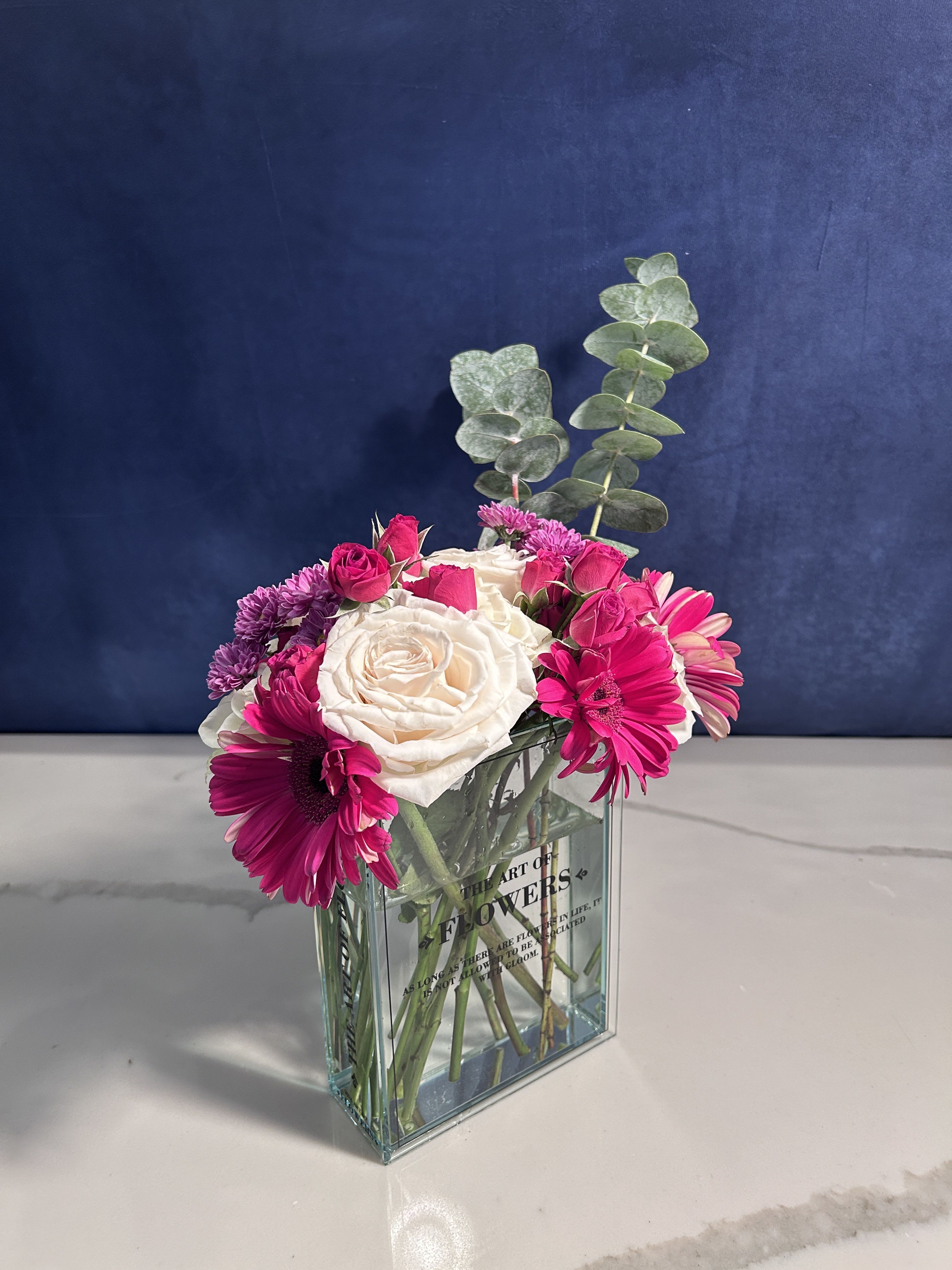 Hidden Gerberas - A powerful display of pinks and white specially arranged in our Bookworm vase.   Gerbera Daisies, Roses, Button Mums, Spray Roses, Spiral Eucalyptus