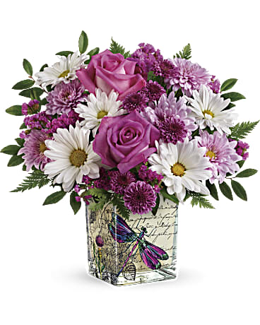Wildflower In Flight Bouquet Wildflower In Flight Bouquet - With its feminine feel and European charm, this alluring glass cube is the perfect Mother's Day surprise! It's carefully hand-decorated and filled with a fresh bouquet of daisies and roses. This bright bouquet includes hot pink roses, purple button spray chrysanthemums, lavender cushion spray chrysanthemums, white daisy spray chrysanthemums, raspberry sinuata statice, leatherleaf fern, and huckleberry.