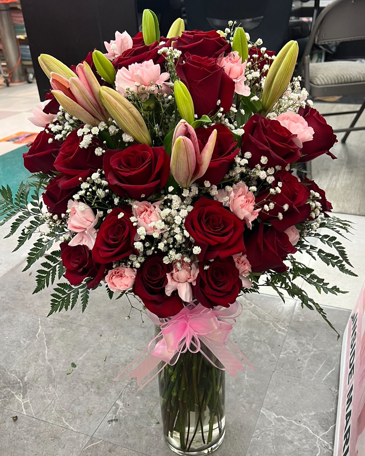 Lily Rose Love Arrangement  - Standard size  comes with 12 roses , 2 lily stems  and 6 carnations , the deluxe size comes with 3 Lilies stems , 12 carnations and 25 red roses  . 