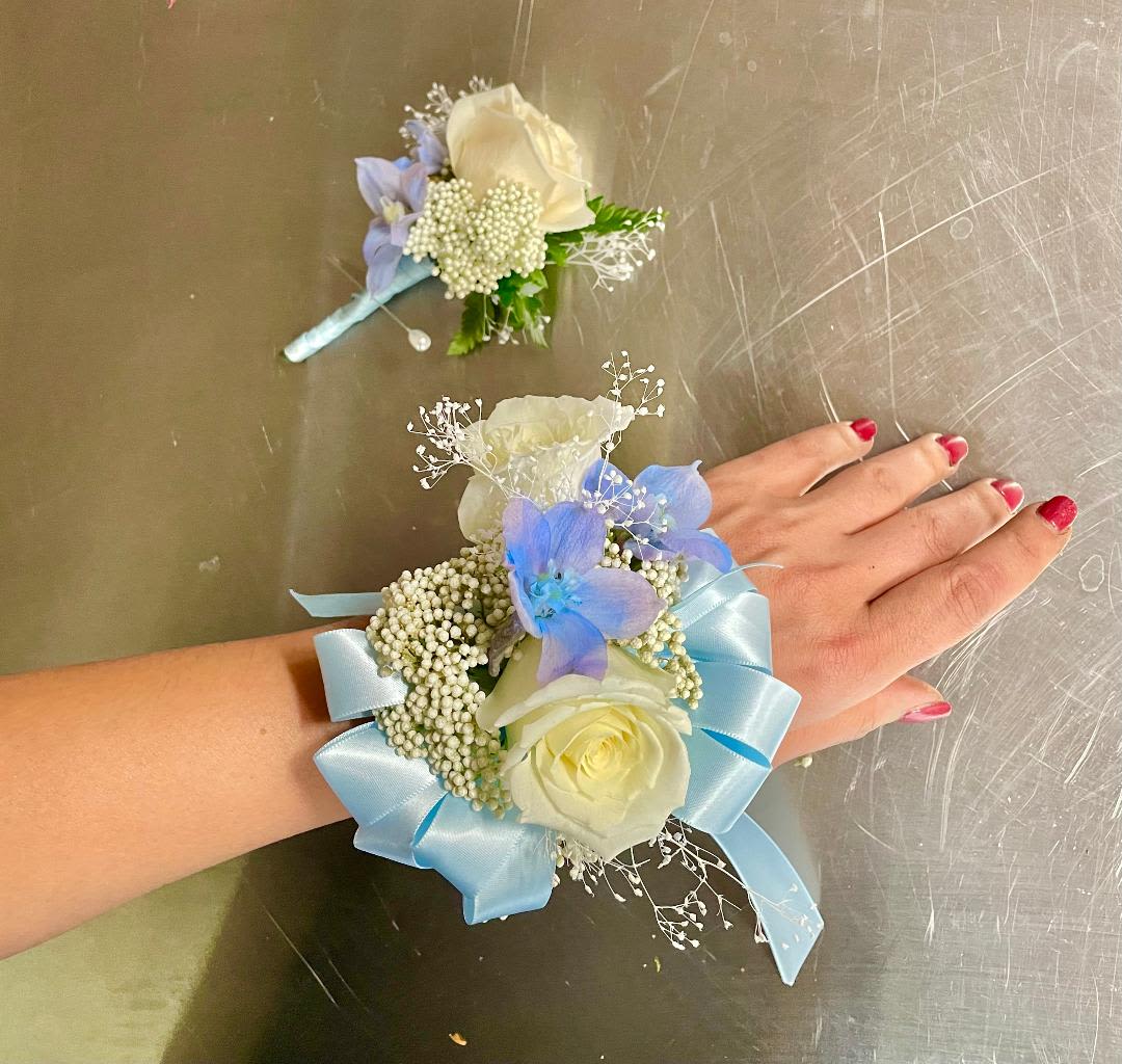 Rose Haven Corsage and Boutonniere Set - Made from fresh flowers, a corsage looks like a petite flower arrangement (typically consisting of just one or several smaller blooms) and usually sits on the wrist like a bracelet, though it can also be pinned on a lapel. Corsages serve as a way to honor people who are very important to the couple getting married. Please contact our shop at (747) 249-4678 for any customization. 