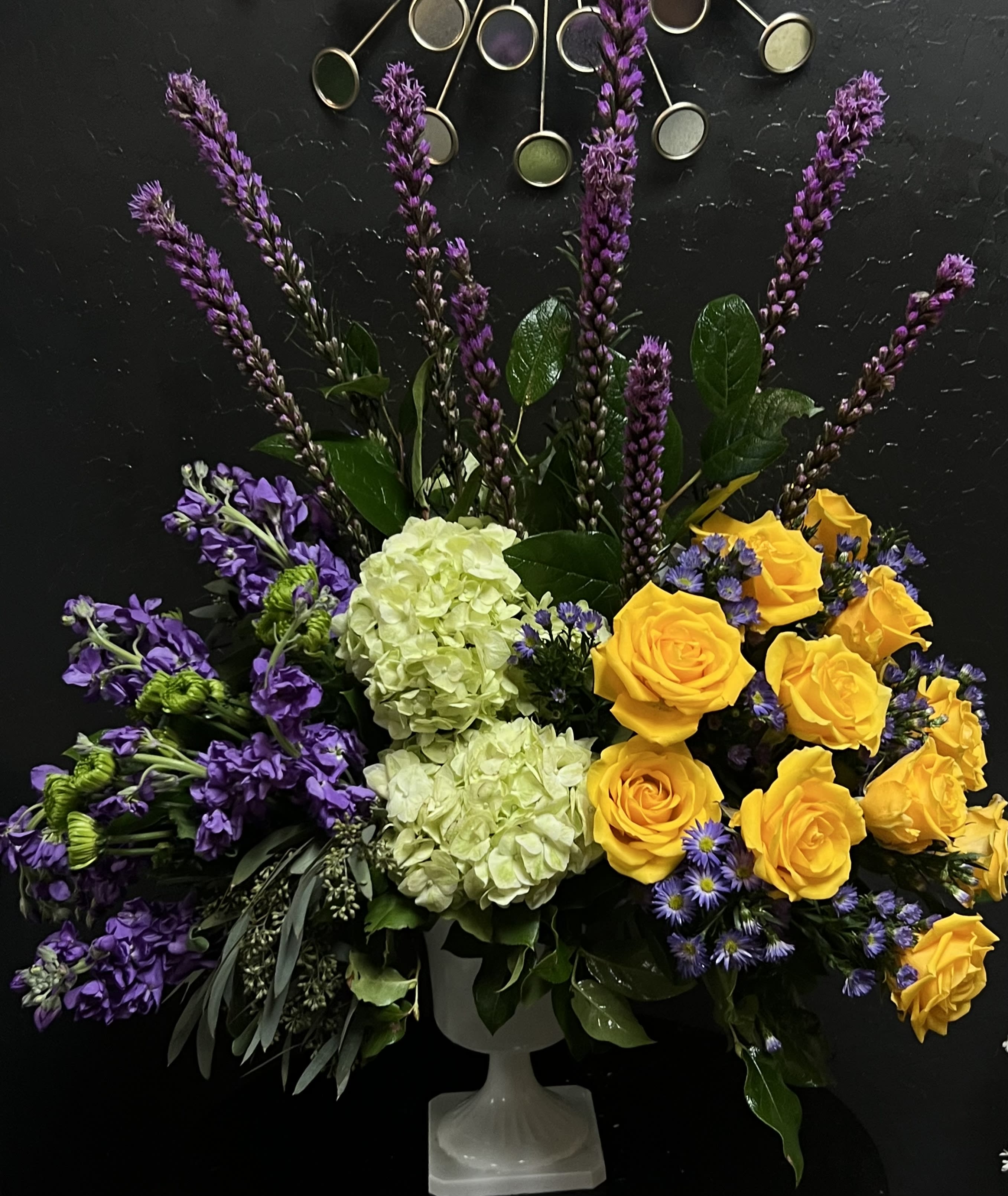 The FTD Affection Arrangement The FTD Affection Arrangement - Contrasting blooms of purple green and yellow create an original and beautiful expression of sympathy and sorrow eminently appropriate for celebrating a life that has passed. This stately arrangement handcrafted by a local FTD artisan florist features an eye catching silhouette of purple liatris stretching heavenward surrounded by yellow roses purple stock lavender Monte Casinos and green hydrangea and button poms in a pedestal urn with the look of fine white ceramic. This “statement bouquet” makes a welcome addition to a wake funeral or graveside burial service.