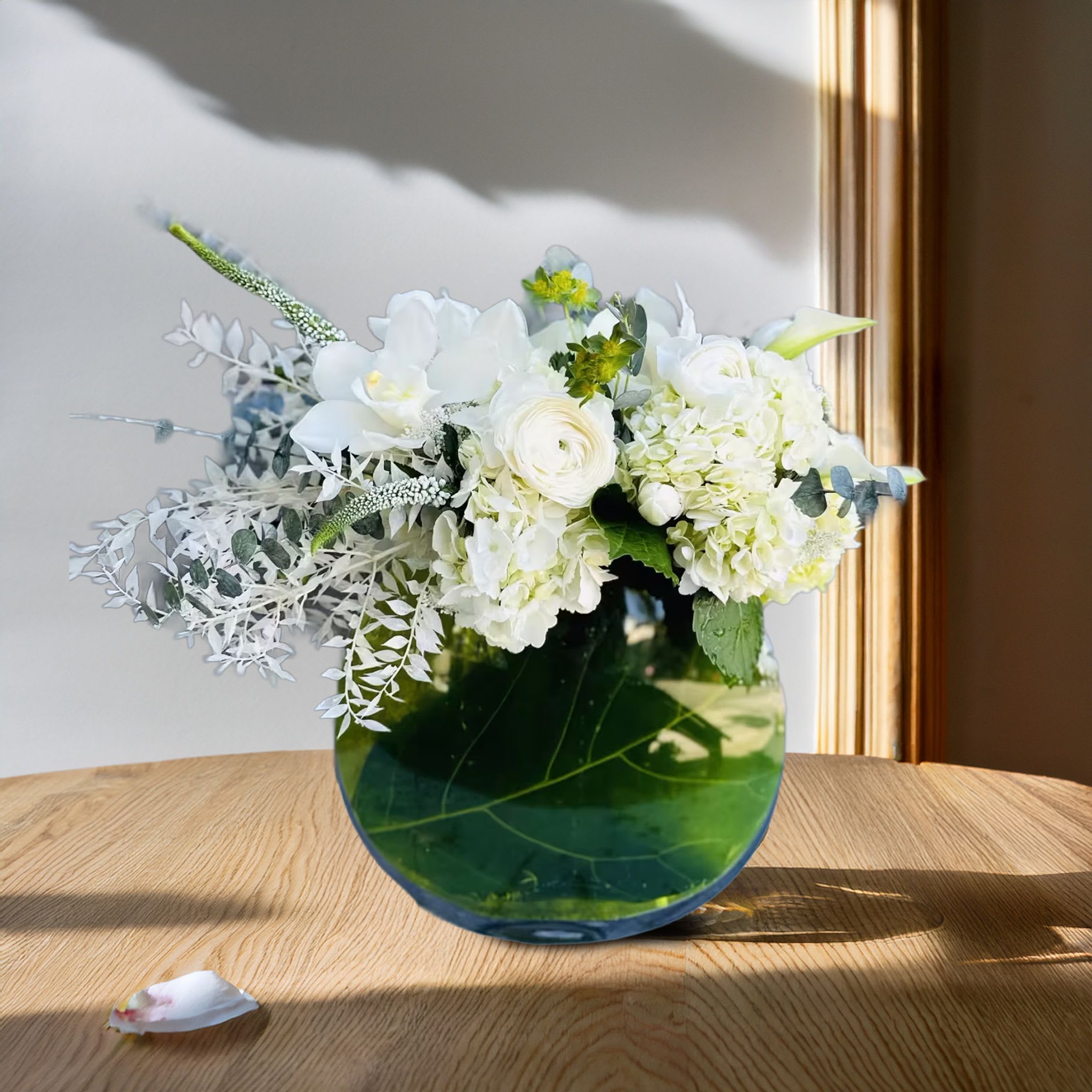 Fiddle Luxe <3 Fiddle Luxe <3 - Understated yet undeniably luxurious, this elegant all-white floral arrangement embodies refined sophistication and clean, modern design. Carefully arranged in a clear round glass vase lined with a broad green tropical leaf, this composition features a curated mix of white florals including hydrangeas, lisianthus, roses, snapdragons, and veronica. Delicate bleached ruscus adds a soft, ethereal texture that contrasts beautifully with the structured round shape of the vase and the dense clusters of blooms. The design is airy and serene, with a balanced silhouette that feels both minimal and full. Perfect for contemporary interiors, sympathy gestures, weddings, spa environments, or high-end hospitality suites, this arrangement is a go-to for clients seeking purity and elegance in floral form. Its clean palette and sophisticated styling make it ideal for art galleries, hotel lobbies, real estate showings, and editorial styling. Whether sent as a thoughtful gift or placed as a centerpiece, this design speaks of tranquility, grace, and elevated taste. Touch of Orchids LA offers same-day flower delivery across Los Angeles, including Beverly Hills, Brentwood, West Hollywood, Malibu, and Pasadena. This arrangement is a favorite for minimalist luxury gifting, corporate floral installations, and refined home accents.