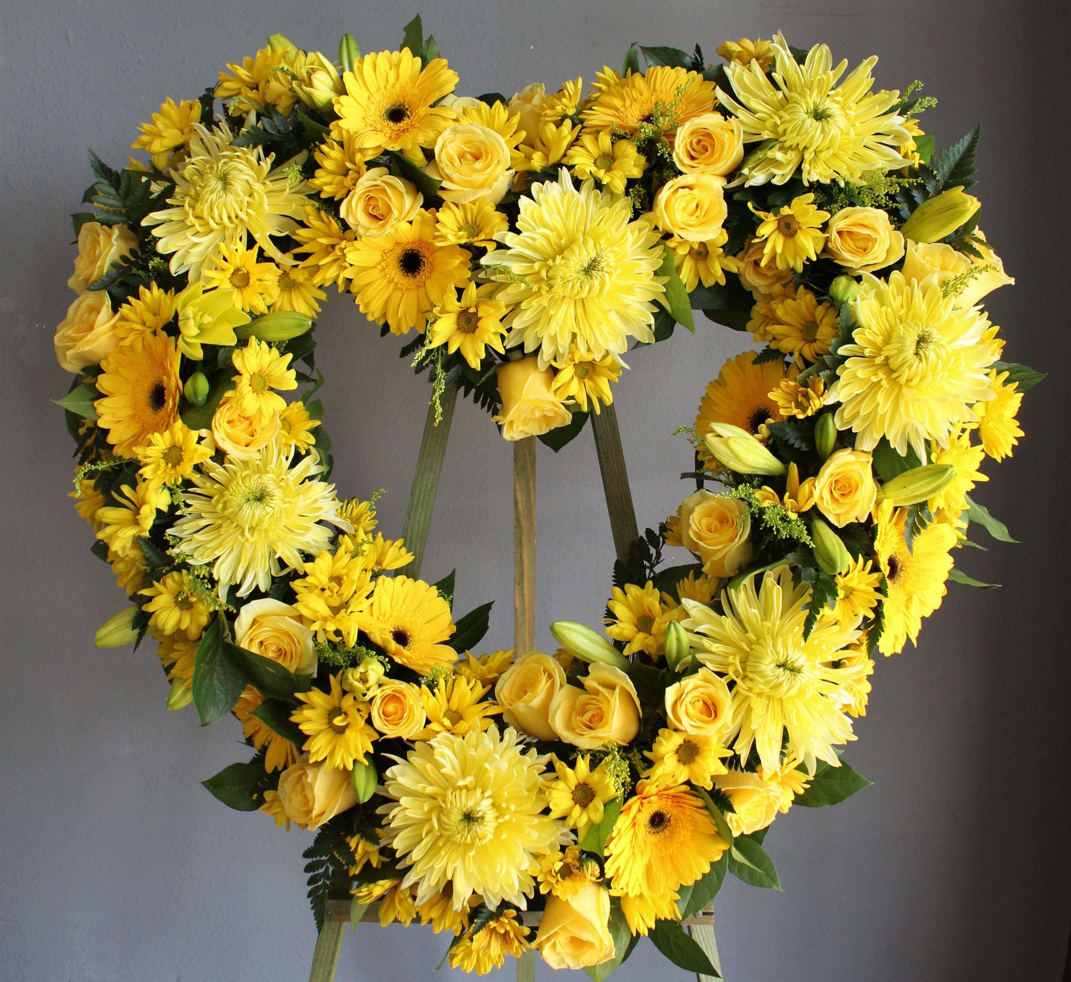FUNERAL HEART WREATH - I Carry Your Heart 75 - This is a bright option for a funeral service, church or graveside. This open heart arrangement will be designed with an 18&quot;, 24”, or 30&quot; heart form and will be delivered on a stand. This lovely mix of yellow roses, daisies and lilies is the perfect way to add some brightness and color to a day of remembrance.   **This is a piece for a funeral or memorial service. Please place the order at least 2 days prior to the service to guarantee a certain arrangement. Anything sooner and we cannot guarantee it will match the picture. These pieces can be customized to the color of your choice. The flowers may vary depending on availability of the flowers, special requests and quality of the flowers we have in stock. If you have a special request please add it to our special instructions when placing your order. If you have any questions please don’t hesitate to call. 714 289 1123**