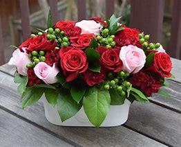 Romance in Bloom Centerpiece Romance in Bloom Centerpiece - Celebrate love in full bloom with the Romance in Bloom Centerpiece, an elegant arrangement designed to capture hearts. This charming bouquet features a beautiful blend of lush red and soft pink roses, accented with vibrant green hypericum berries and fresh, rich greenery. The flowers are perfectly nestled in a sleek, modern white ceramic container, creating a sophisticated look that complements any setting. Ideal as a centerpiece for romantic dinners, a heartfelt gift for your Valentine, or a stunning décor piece, this arrangement is sure to make a lasting impression. Why It’s Perfect for Valentine’s Day: Red & Pink Roses: Symbolize deep love, admiration, and tenderness. Vibrant Green Accents: Add freshness and contrast for a lively, romantic touch. Elegant White Container: A sleek, reusable piece that enhances any space. Perfect for Any Occasion: A versatile arrangement for romantic gestures, anniversaries, or heartfelt surprises.