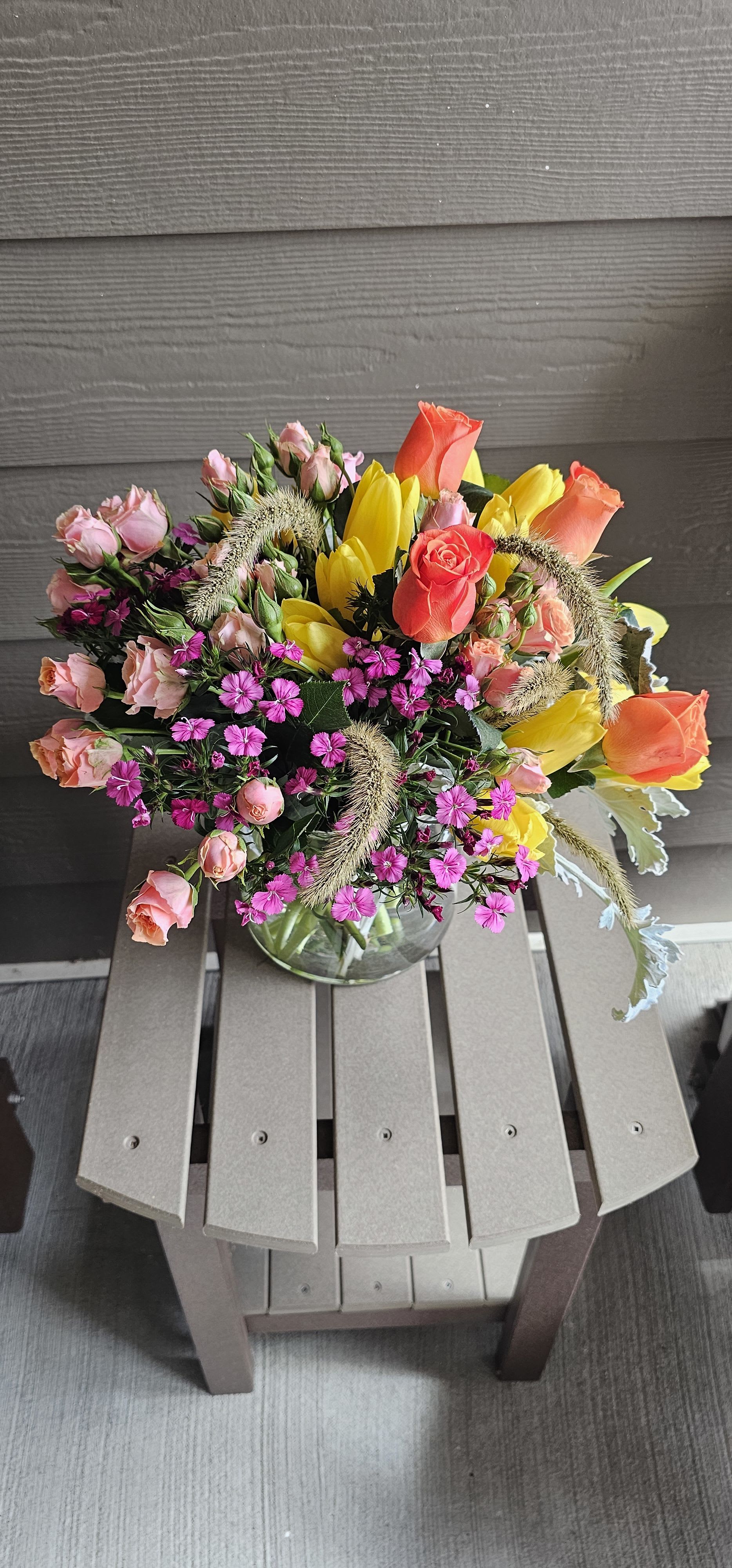 Sunshine Meadow Bouquet  -  A Joyful Burst of Color &amp; Energy – Bright and bold, this bouquet features sunny yellow tulips, vibrant coral roses, soft peach spray roses, and cheerful pops of fuchsia dianthus, creating a vibrant mix that instantly lifts the mood.   Garden-Fresh &amp; Whimsical – Designed with a natural, meadow-inspired flair, including playful wisps of greenery and ornamental grass, the Sunshine Meadow Bouquet brings the feeling of springtime fields right to your doorstep.   Versatile &amp; Uplifting – This cheerful arrangement is perfect for birthdays, congratulations, get-well wishes, or just because. It’s a fresh pick-me-up that feels like sunshine in a vase.   Designed in a classic clear vase, this bouquet offers a clean, modern look while allowing the bright blooms to shine.   Why Customers Love It: ️ Bright, mood-boosting colors ️ Fresh, seasonal feel with whimsical texture ️ Ideal for gifting or decorating   Available for Same-Day Delivery  Limited availability—order now for guaranteed delivery!  