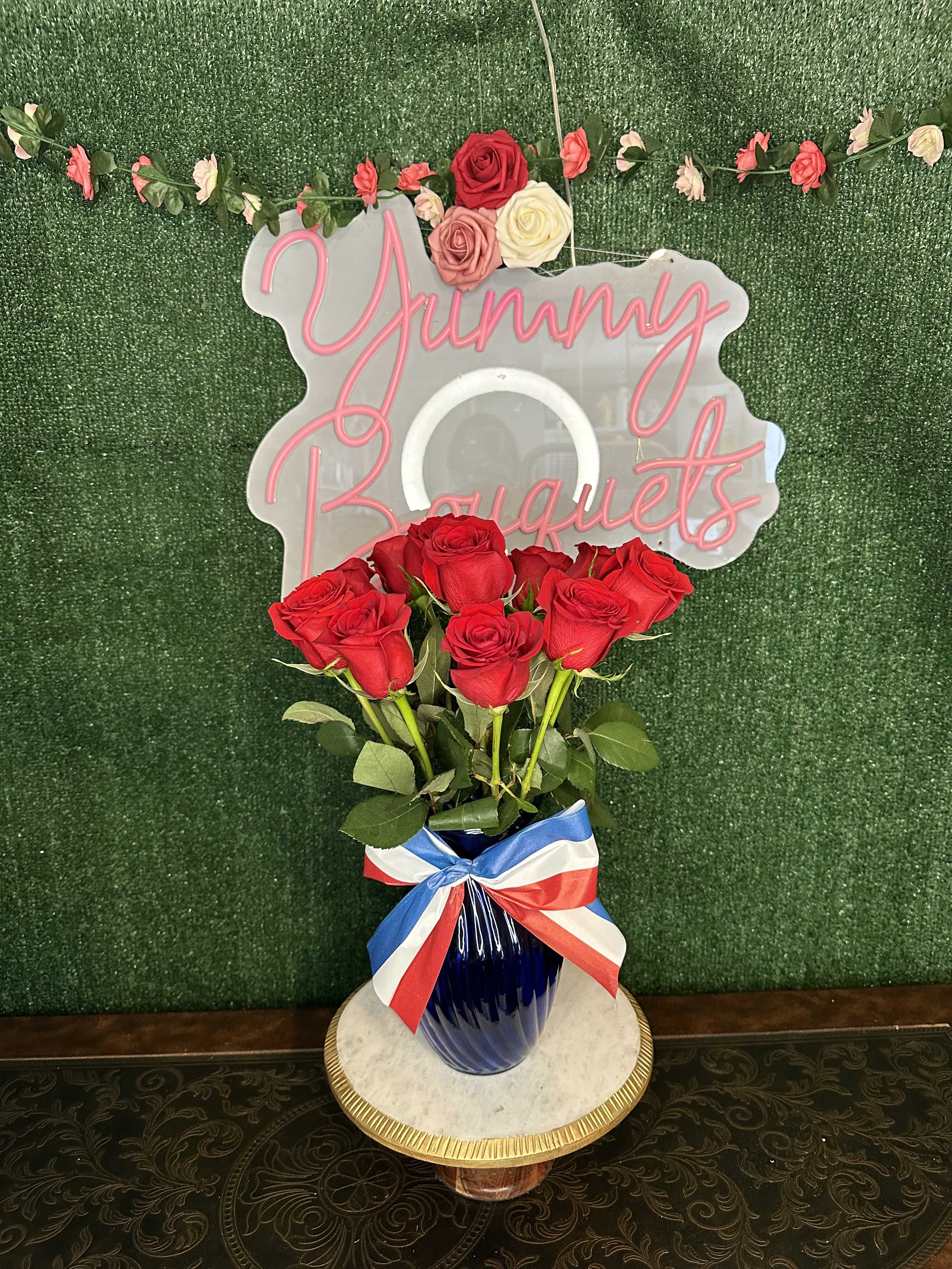 Patriotic blue Patriotic blue - Red roses on a blue vase with patriotic ribbon "Picture is a reference every arrangement would not be exactly the same. Color Substitution may apply. Flowers and color substitution may apply"