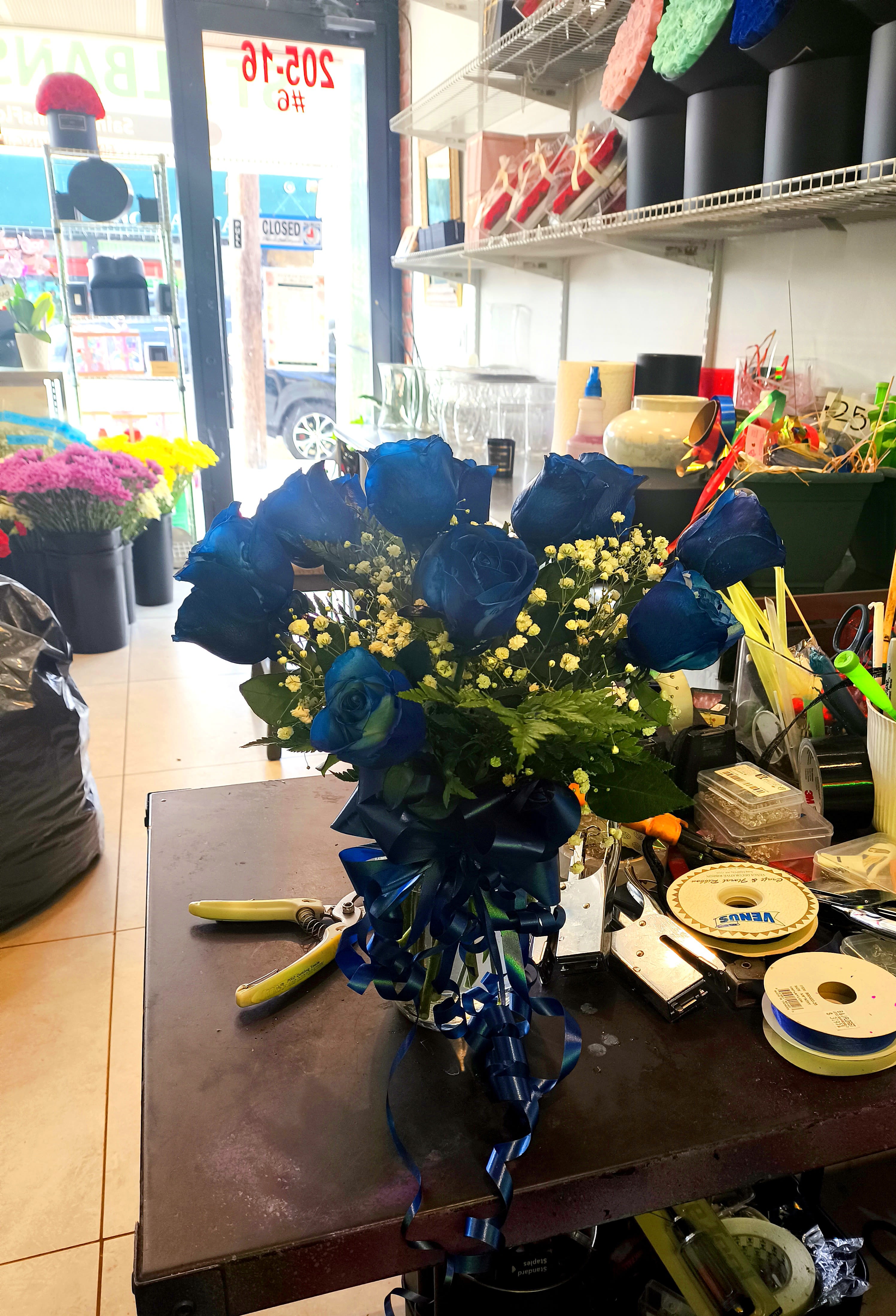 BLUE ROSE ARRANGEMENT - We take 12 blue roses and arrange them in a vase with baby's breath and greenery with diamonds in the blue roses.