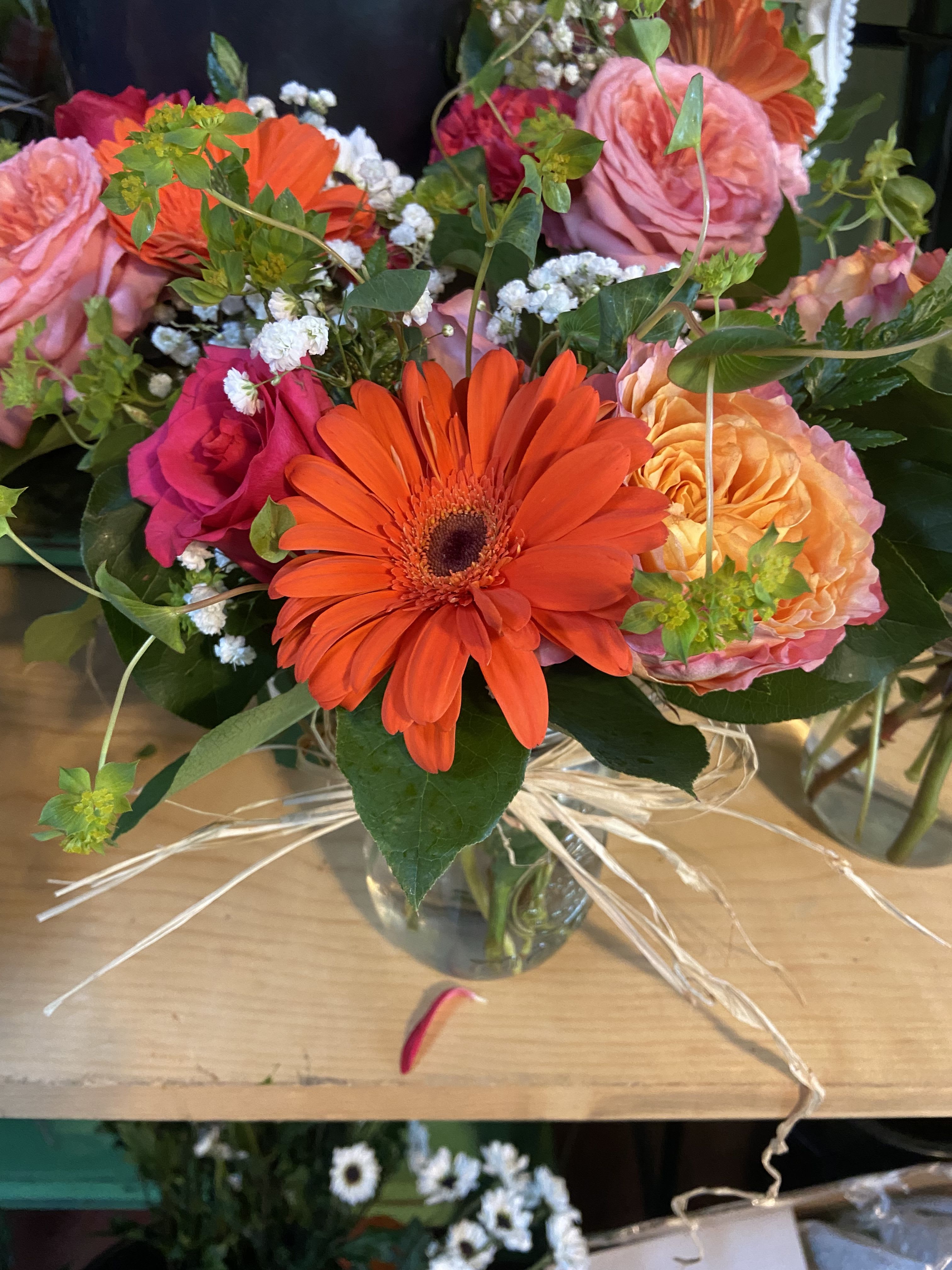 Bursting with color  - Orange gerbers ,peach roses , hot pink roses,medium pink garden rose , babies breathe,  bluplerum Salal in glass vase 