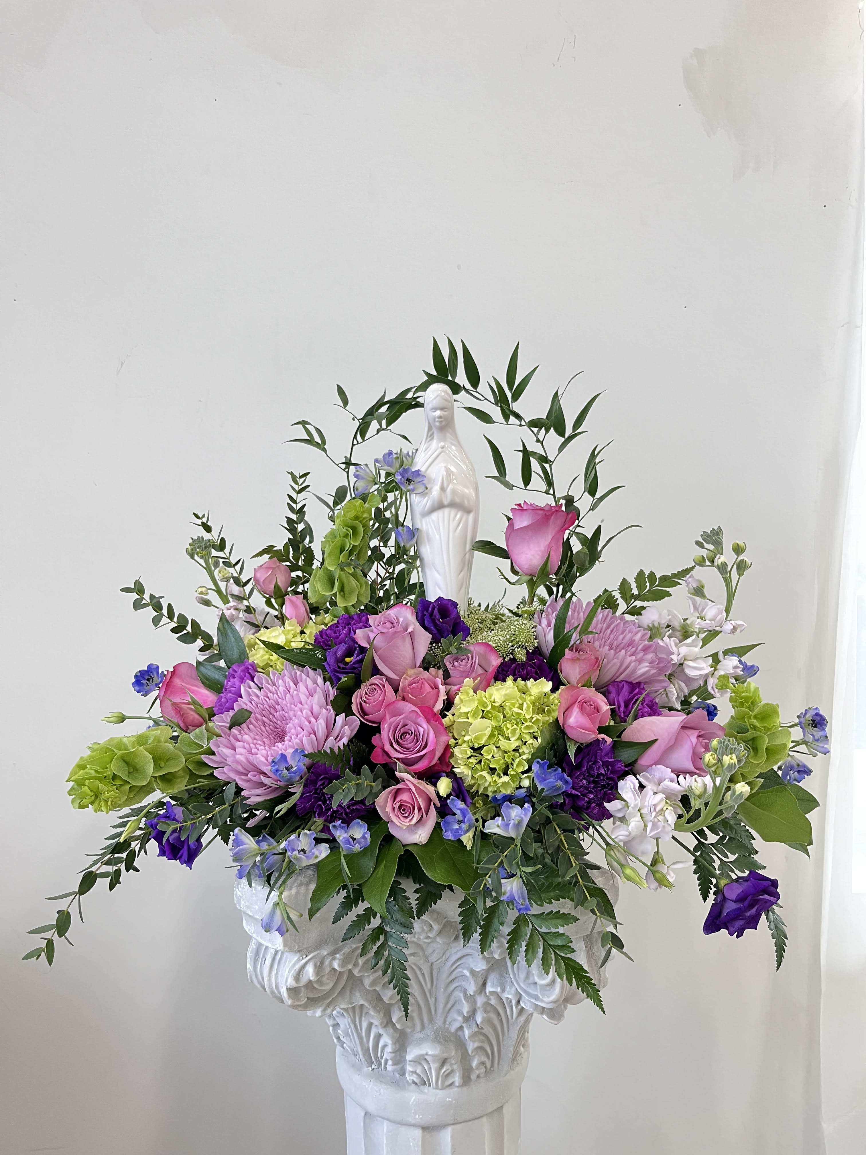 Madonna Grace by Westford Florist Art by Veny Madonna Grace by Westford Florist Art by Veny - Losing a loved one brings profound sorrow, and finding the right words can feel impossible. The Madonna Grace One Sided Sympathy Arrangement by Westford Florist Art by Veny serves as a heartfelt reminder of love and remembrance during these difficult times. Elegantly curated with fresh blooms in soft hues, this exquisite arrangement beautifully honors cherished memories while providing solace to those who are grieving. A thoughtful gesture that speaks volumes, the Madonna Grace is designed not only to express your condolences but also to celebrate a life filled with grace and beauty. Share your support with an arrangement that encapsulates both compassion and reverence. Crafted with care by expert florists at Westford Florist, every element in this arrangement has been thoughtfully selected to create a truly meaningful tribute. Whether displayed at a funeral or sent as a sympathy gift to a grieving family member or friend, each time it is seen it will serve as a lasting reminder of the cherished memories shared with their loved one. In difficult times like these when words may fall short, but emotions run deep, let the Madonna Grace Sympathy Arrangement offer solace and tranquility. As you pay homage to your dear departed one through this exquisite piece from Westford Florist, it will serve as a timeless reminder of their beauty and grace that will forever live on in our hearts.