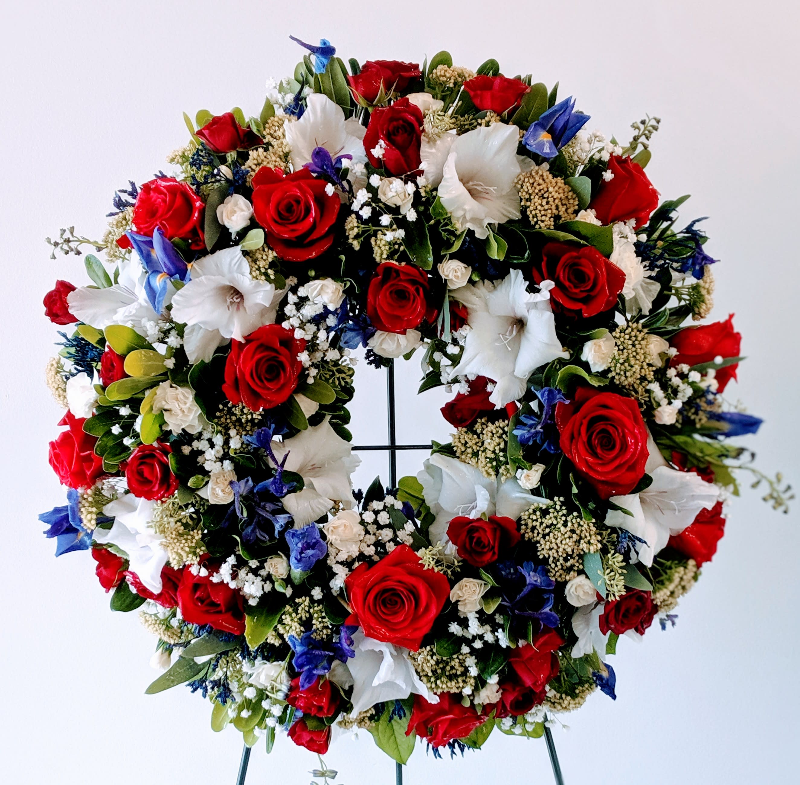 Patriot by Westford Florist Art by Veny Patriot by Westford Florist Art by Veny - The Patriot Sympathy Arrangement by Westford Florist Art by Veny is a heartfelt tribute designed to honor the lives and sacrifices of our military heroes and veterans. This elegant standing wreath combines stunning blooms with thoughtful craftsmanship, embodying grace and dignity in every petal. Each arrangement reflects reverence for those who served selflessly, making it an ideal choice for commemorating their dedication to our country. Show your support and pay tribute with this meaningful floral expression that conveys deep respect and admiration during times of remembrance. The Patriot Sympathy Arrangement can be presented at any event honoring our fallen heroes - from funerals to Memorial Day services or any other remembrance ceremony. It adds an elegant touch to these solemn occasions while serving as a symbolic representation of remembrance. Honor them in style with this exceptional standing wreath from Westford Florist. Let its beauty speak volumes about your gratitude towards these brave souls who will forever hold a special place in our hearts. Choose the Patriot Sympathy Arrangement today and let us together pay tribute in honor of those who have served our country with unwavering dedication and courage.