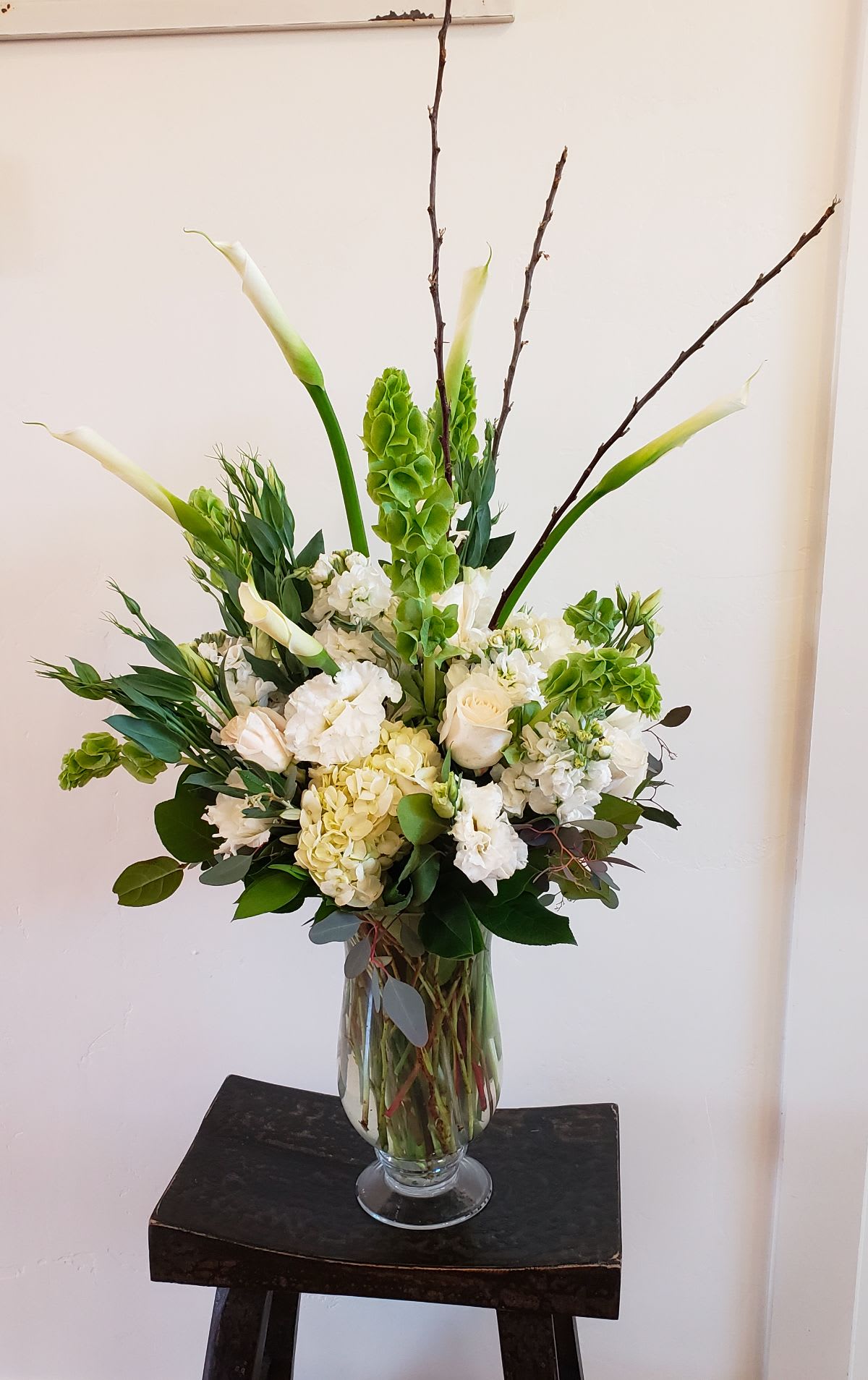 NEW! Comforting Light NEW! Comforting Light - A tall arrangement dressed in white calla lilies, lisianthus, hydrangea, stock and roses.