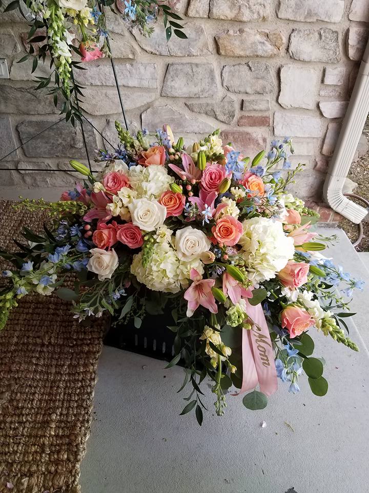Serenity in Bloom Casket Spray by Simply Flowers - A gorgeous casket spray design filled with lush hydrangea, bi-colored roses, light blue delphinium, and seasonal foliage make up this beautiful tribute for the loss of a loved one. 