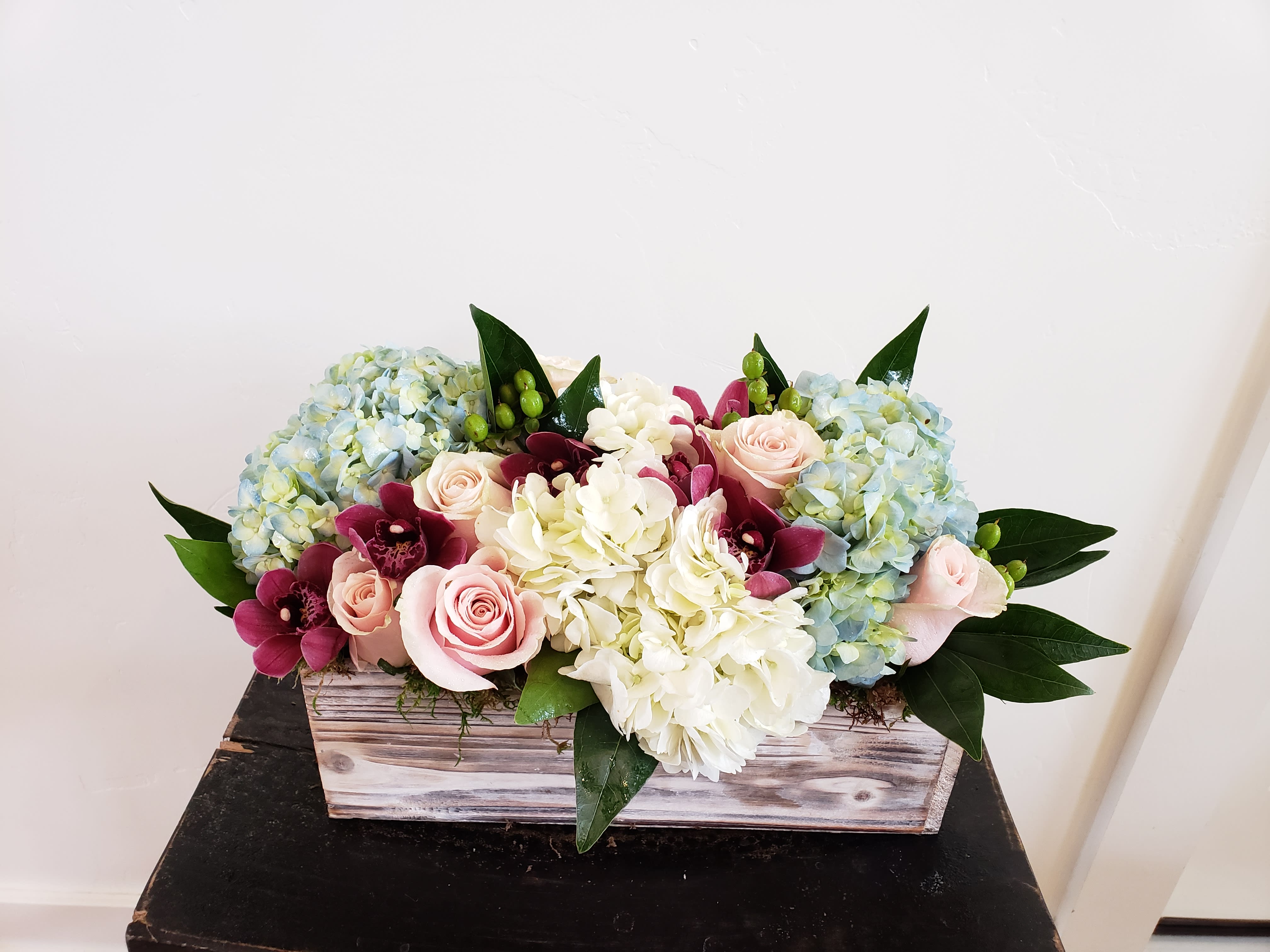 You Had Me At Hello You Had Me At Hello - A beautiful design of fresh, crisp hydrangeas in blue and white, soft pink roses, burgundy cymbidium orchids with a touch of green designed in a long barnwood box.