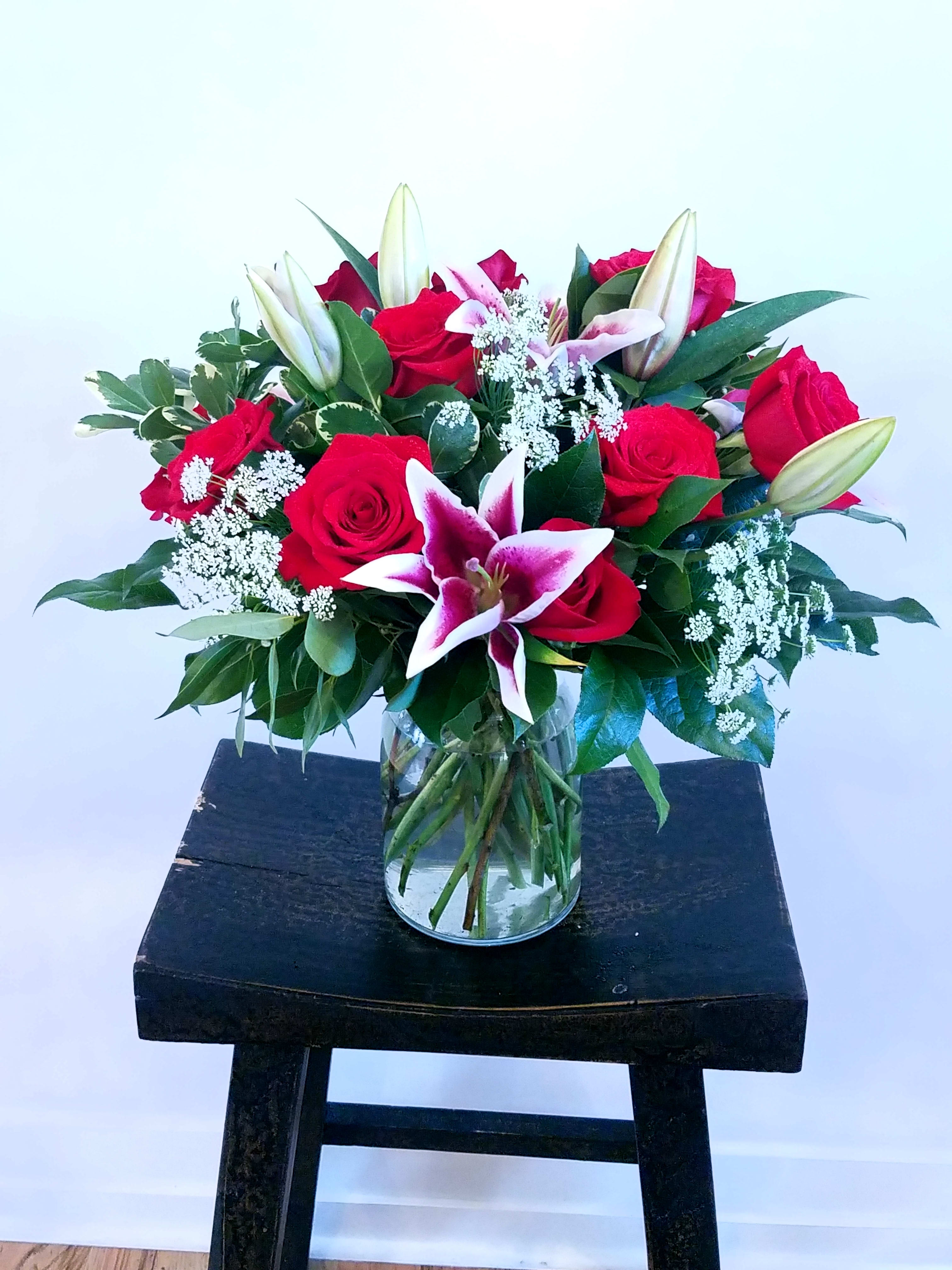 Yours Truly Yours Truly - A classic design that never disappoints. One dozen red roses, fragrant stargazer lilies and Queen Anne's Lace make up this romantic arrangement in a wide mouth vase designed low and lush.