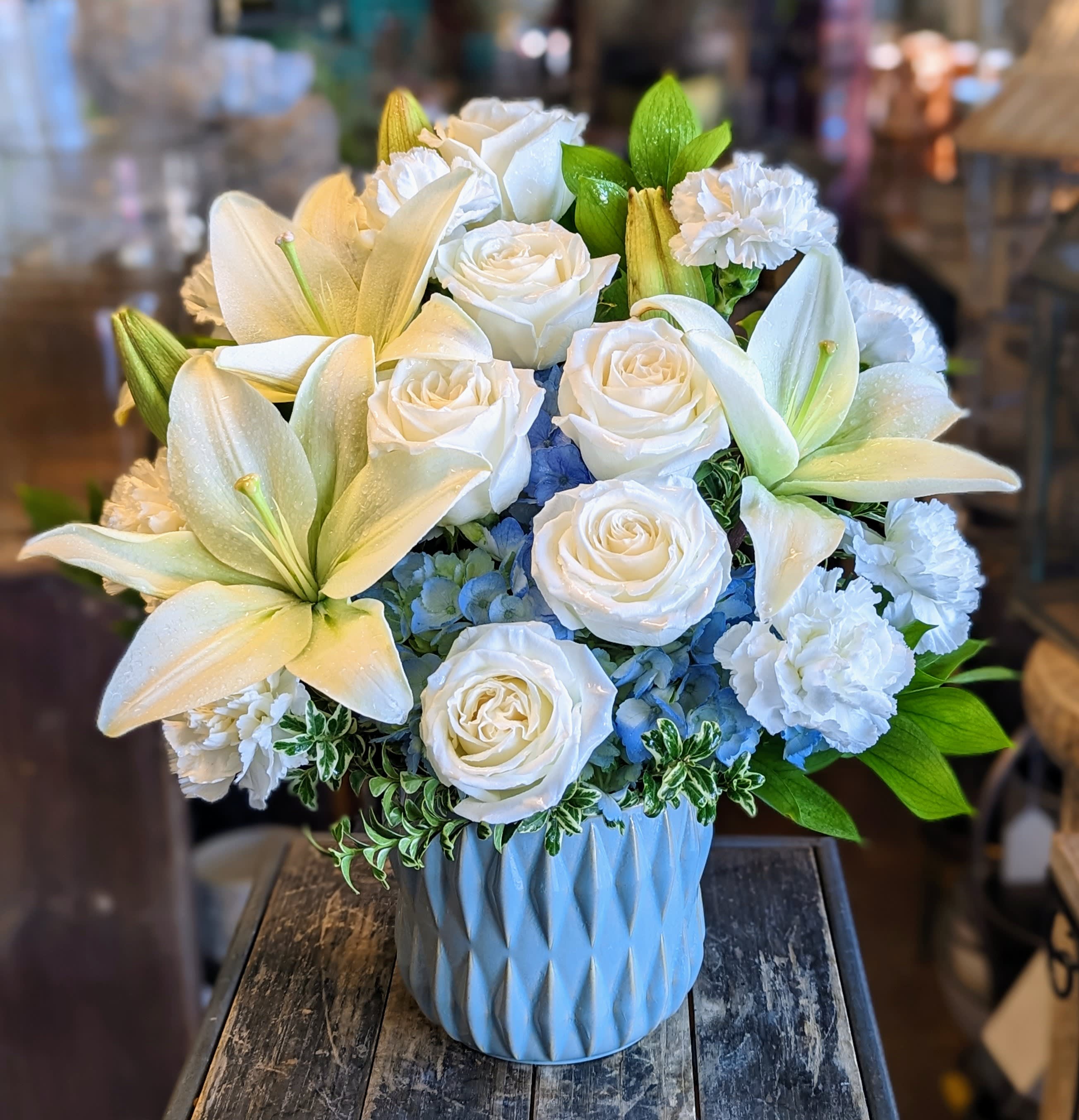 Beautiful Dreams Beautiful Dreams - Beautiful in Blue – Elegant White & Blue Flower Arrangement | Windmill Floral Expressions Las Vegas Graceful. Serene. Unforgettable. Introducing Beautiful in Blue, a signature floral arrangement from Windmill Floral Expressions in Las Vegas. This exquisite bouquet showcases a refined palette of snowy white lilies, creamy roses, fluffy white carnations, and delicate sky-blue hydrangeas, all nestled in a chic, textured blue ceramic vase. Perfectly balancing elegance and tranquility, Beautiful in Blue is a heartfelt gift for sympathy, new beginnings, or simply to say "I'm thinking of you." Each bloom is thoughtfully chosen and artistically arranged by our skilled floral designers to deliver beauty, comfort, and a lasting impression. Whether you're celebrating a special occasion or sending love from afar, Windmill Floral Expressions brings luxury floral design to life — right here in the heart of Las Vegas.