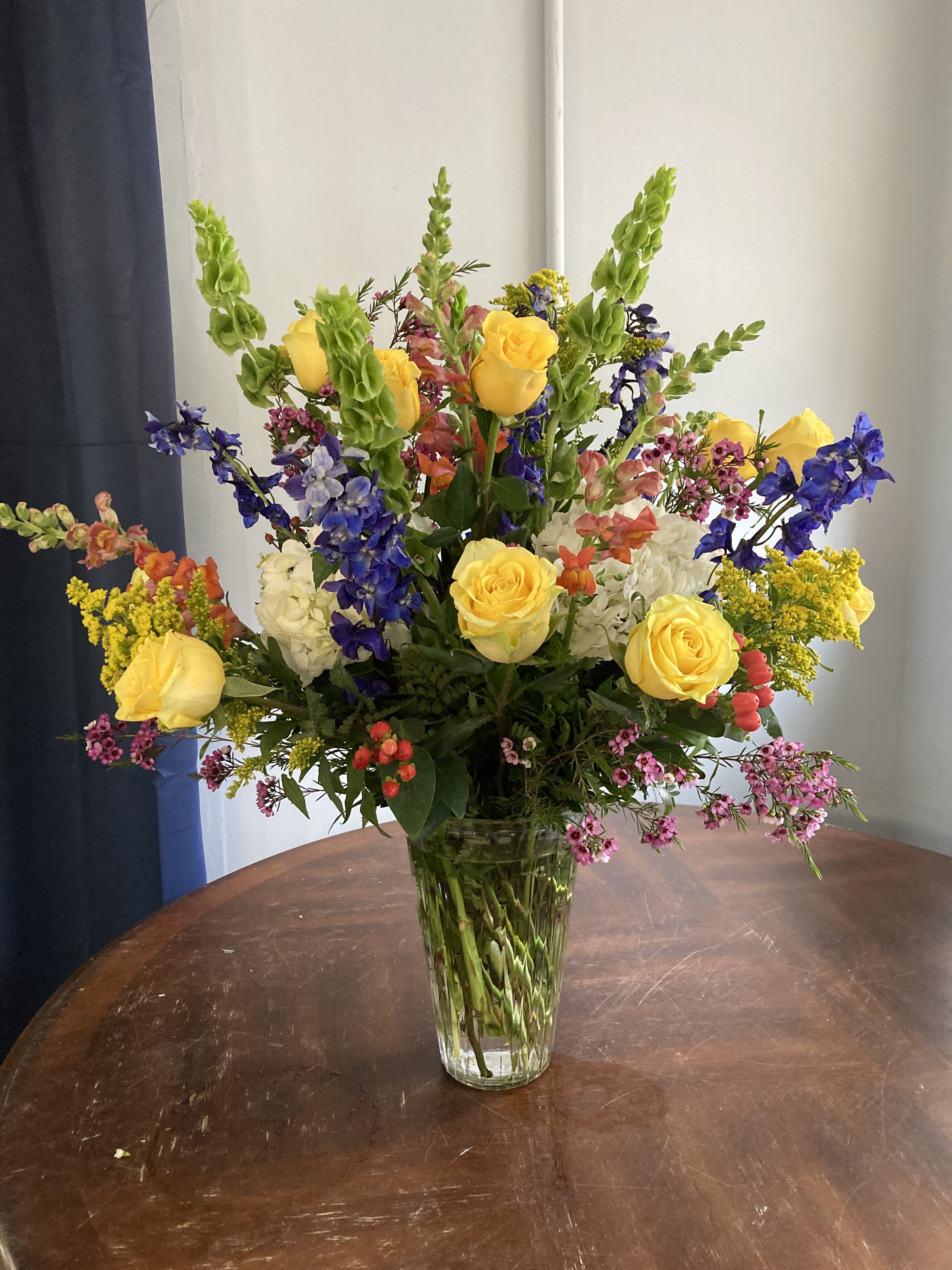 sunny and bright - large arrangement of bright colors such as:  Roses, Hydrangeas, Bells of Ireland, delphinium, snap dragon, hypericum and more