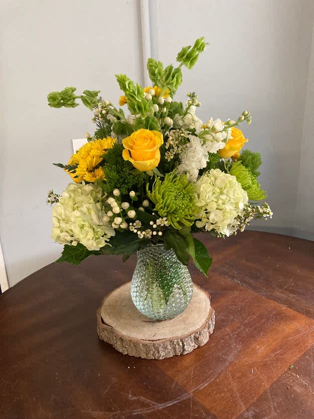 Bright day - this beautiful assortment of green, white and yellow flowers in a vase. Hydrangeas, roses, bells of ireland, fugis, trachilium and hypericum 