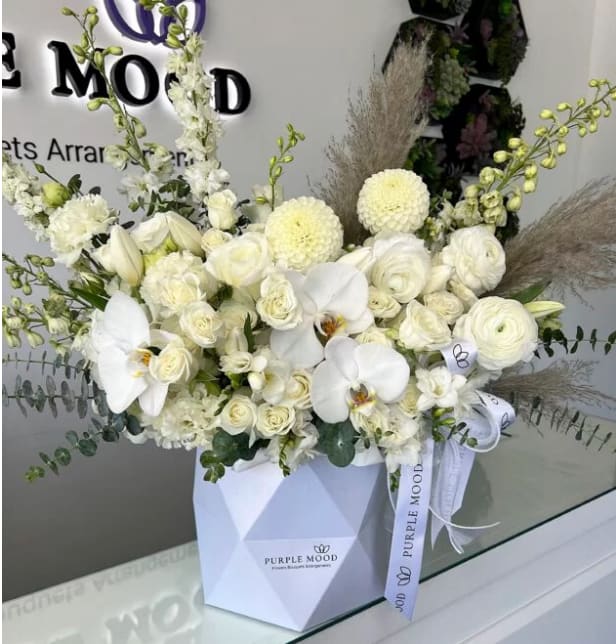 White Bliss Geometric Box White Bliss Geometric Box - "Geometric box with roses, and others flowers. Container size D7.75’x H8.25′ All around arrangement with no lid in back. Box included wet floral foam inside, box doesn’t require vase."