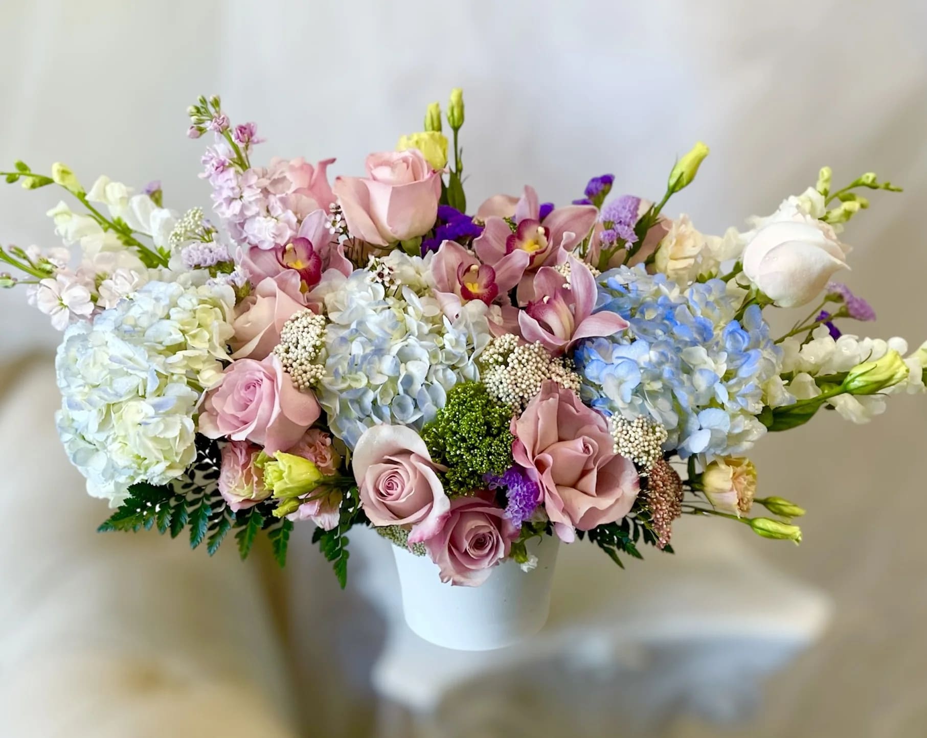 Viva La Vida  - Theme Colors: Shades of white, blue, pink and green   Featured Blooms: Roses, Orchids, Hydrangeas, Snapdragons, Stocks and greens   HK Flowers have a uniqueness of florals and seasonal blooms, certain flowers or colors may not be available as each season affects the availability, color, size, and shape of each floral bloom. Some flowers may be substituted accordingly.   Photos are used as a reference for the color palette and is NOT indicated of the final product. We ask for your trust in us that we will pick out the best seasonal available blooms, while still capturing the arrangements theme and colors mentioned above.