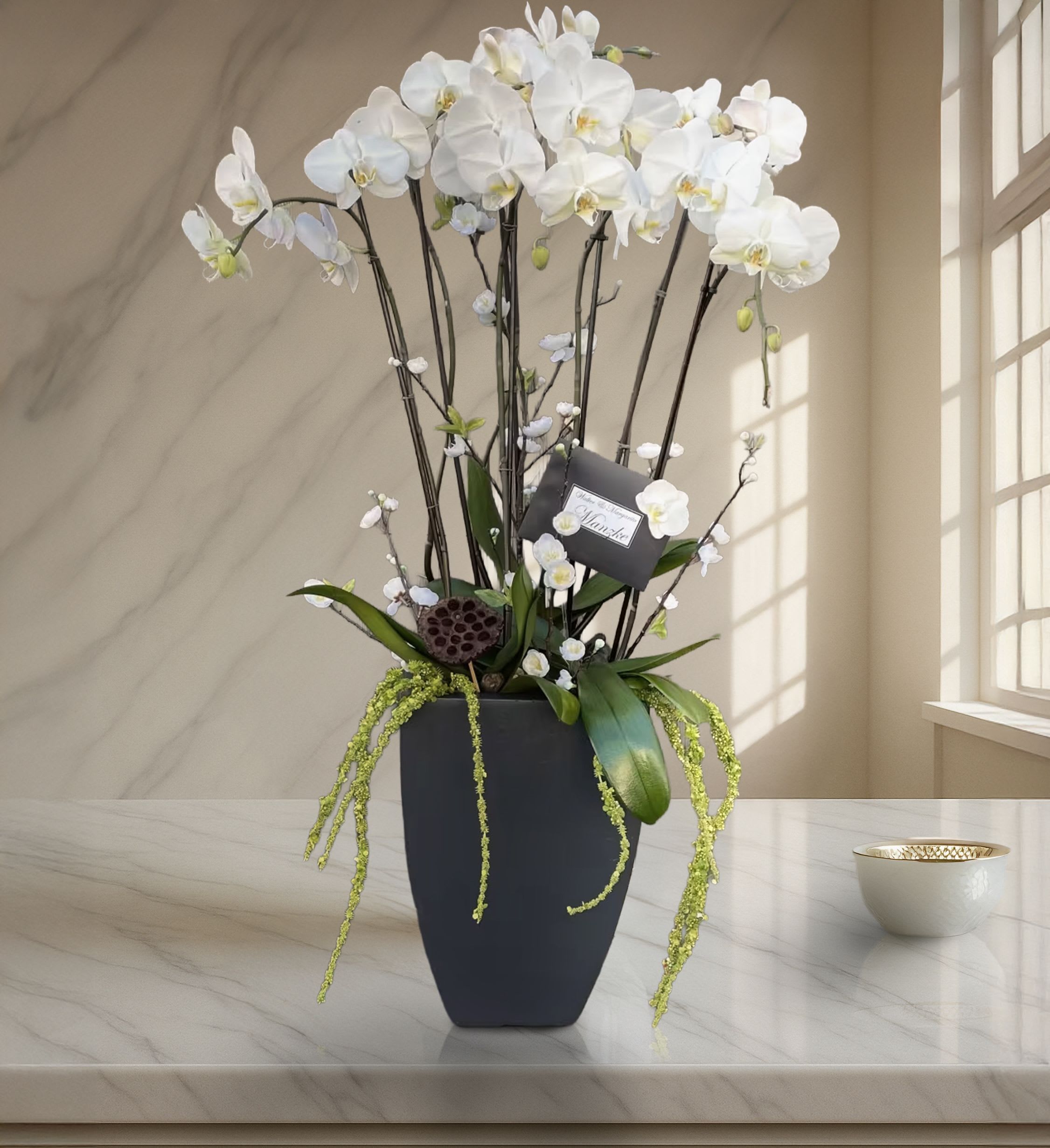 Granite Orchid - Commanding in presence and graceful in design, this grand white phalaenopsis orchid arrangement is the pinnacle of refined floral elegance. Expertly styled in a tall matte black ceramic vase, this luxury piece features multiple stems of cascading white orchids with soft yellow centers, artfully supported by natural branch structures and accented with moss, trailing amaranthus, and lotus pods for an earthy yet elevated finish. The height and fullness of this piece make it an unmistakable statement — ideal for those seeking long-lasting floral impact with timeless beauty.  Perfect for luxury home design, grand hotel lobbies, corporate reception areas, or sophisticated gifting, this orchid arrangement exudes understated opulence. It’s also a distinguished choice for sympathy tributes, high-profile thank-you gestures, or celebratory milestones where elegance is key. With its sculptural form and minimal color palette, this piece fits seamlessly into both contemporary and classic settings.  Touch of Orchids LA provides same-day orchid delivery across Los Angeles, including Beverly Hills, Downtown LA, Pacific Palisades, West Hollywood, and Malibu. This piece is part of our Grand Orchid Series and is frequently selected for executive gifting, upscale interior staging, and special commemorations.