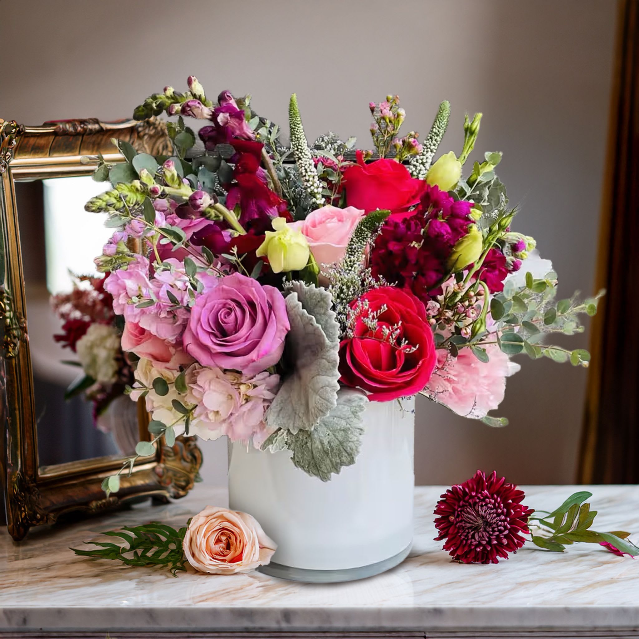 Jasmine <3 Jasmine <3 - Lush, expressive, and full of vibrant romance, this jewel-toned floral arrangement is a luxurious blend of color, texture, and elevated design. Artfully arranged in a clean white ceramic vase, this composition features bold red roses, lavender roses, blush lisianthus, deep burgundy snapdragons, soft pink hydrangeas, and sprigs of waxflower. Textural accents like dusty miller and seeded eucalyptus bring a soft silvery contrast, while the mix of upright and trailing elements adds movement and balance to the overall form. Perfect for romantic gestures, anniversaries, birthdays, or luxurious home styling, this piece makes a rich statement that’s equal parts classic and contemporary. Whether placed on a marble countertop, styled in an entryway, or delivered as a heartfelt gift, it offers both emotional impact and refined beauty. Touch of Orchids LA provides same-day flower delivery across Los Angeles, including Beverly Hills, Hancock Park, West Hollywood, Studio City, and Santa Monica. This design is part of our Romantic Jewel Collection, curated for clients seeking lush florals with a rich, designer finish.