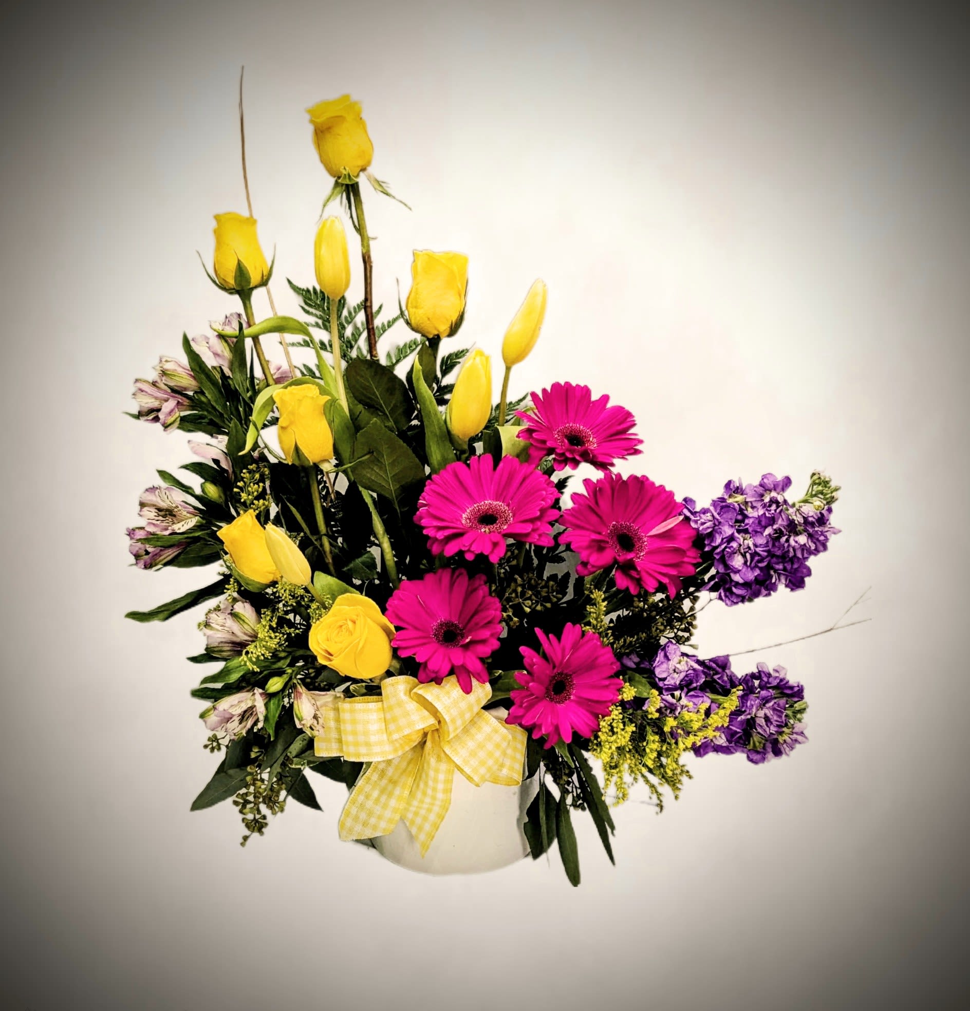 Sunshine and smiles bouquet Sunshine and smiles bouquet - Brighten anyone’s day with our Sunshine & Smiles bouquet! This cheerful design combines the sunny charm of yellow roses and tulips with the bold pop of magenta gerbera daisies and accents of lavender stock and delicate alstroemeria. Nestled in a classic white container and tied with a yellow gingham bow, it's a perfect gift for celebrations, thank-yous, or simply sending joy.