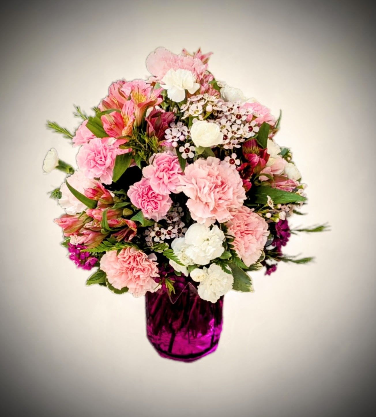 Blushing Petals Blushing Petals - Sweet, soft, and full of charm, Blushing Petals is a celebration of gentle beauty. This bouquet features layers of lush pink and white carnations, vibrant alstroemeria, and delicate waxflowers, all gathered in a striking fuchsia vase that adds a bold pop of color. Accented with fresh greenery, it’s the perfect arrangement to share love, gratitude, or simply brighten someone’s day with a splash of floral delight. Ideal for birthdays, get well wishes, or just because.