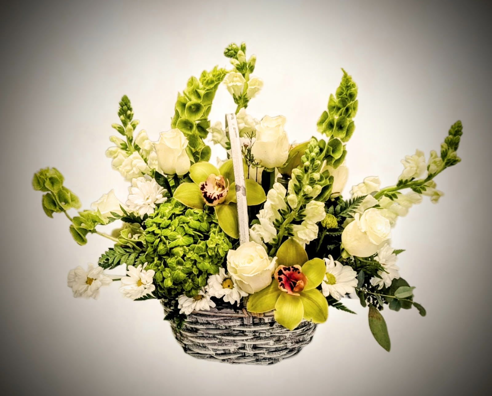 Whispers of Serenity Basket Whispers of Serenity Basket - A gentle expression of peace and grace, the Whispers of Serenity Basket features a lush collection of soft white roses, delicate snapdragons, crisp hydrangeas, and stunning green cymbidium orchids. Accented with fresh greenery and arranged in a rustic woven basket, this arrangement radiates calm and natural beauty. Ideal for sending comfort, celebrating new beginnings, or simply sharing a moment of tranquility.