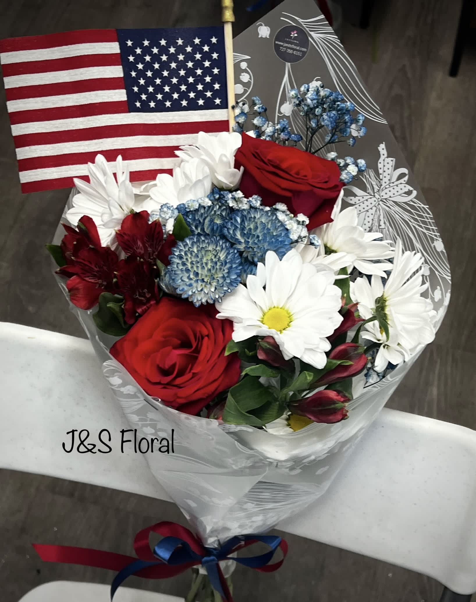 Courage in Colors  - Introducing our design Courage in Colors! Beautifully arranged with roses, Daisies, Alstro, button fillers and greenery wrapped with red blue ribbons and comes with the flag. 