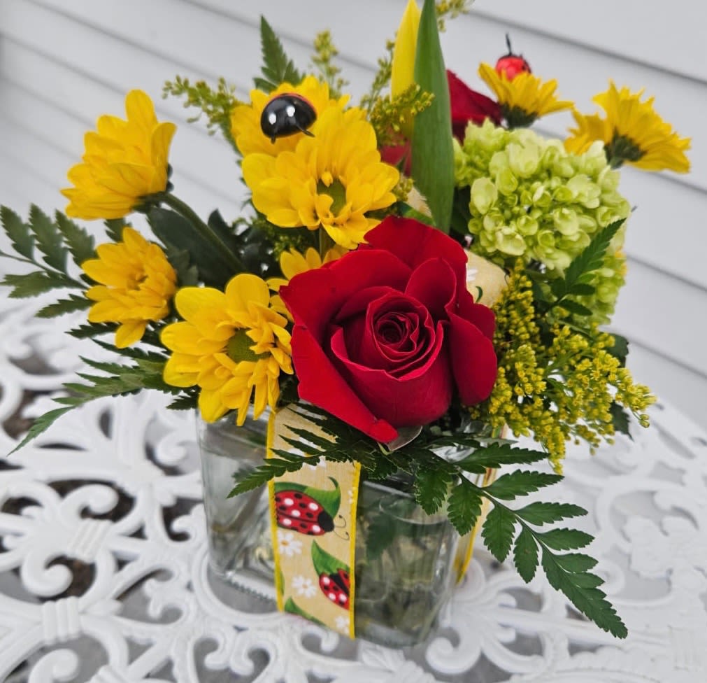 Lady Bug Bouquet - Yellow daisies, green hydrangea, red roses. solidago arranged in a cube vase tied with lady bug ribbon