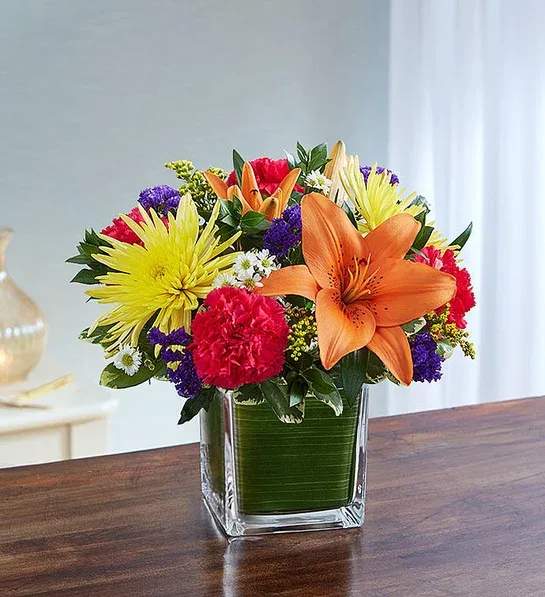 Healing Tears™ Multicolor Bright - Arrangement of hot pink roses and carnations, orange Asiatic lilies, yellow spider mums, purple statice and white monte casino; accented with fresh greenery Artistically designed by our florists in a classic clear glass cube lined with a Ti leaf ribbon; vase measures 5&quot;H x 5&quot;D Premium arrangement measures approximately 11&quot;H x 11&quot;L Deluxe  arrangement measures approximately 10&quot;H x 10&quot;L Standard arrangement does not include roses and measures approximately 9&quot;H x 9&quot;L Perfect gift for delivery to the homes of family members or friends Our florists hand-design each arrangement, so colors, varieties, and container may vary due to local availability Lilies may arrive in bud form and will open to full beauty over the next 2-3 days