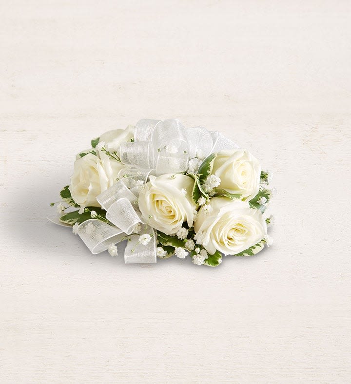 White Rose Corsage *PICK UP ONLY* - A stunning, handcrafted corsage featuring elegant white roses and fresh greenery accents, perfect for events like proms, weddings, school dances, or any special occasion. Each arrangement is uniquely designed by our expert florists, so flower varieties, colors, and containers may vary based on availability.  Standard has 5 mini roses (suitable for children and teens) Deluxe has 6-7 mini roses, depending on size of bloom. (suitable for adults and young teens)  *****For custom designs, ribbon colors, or special additions like rhinestones or pearls, please give us a call. *****To guarantee your order is ready in time, contact us at least 24 hours in advance, as each corsage is meticulously made by hand. 