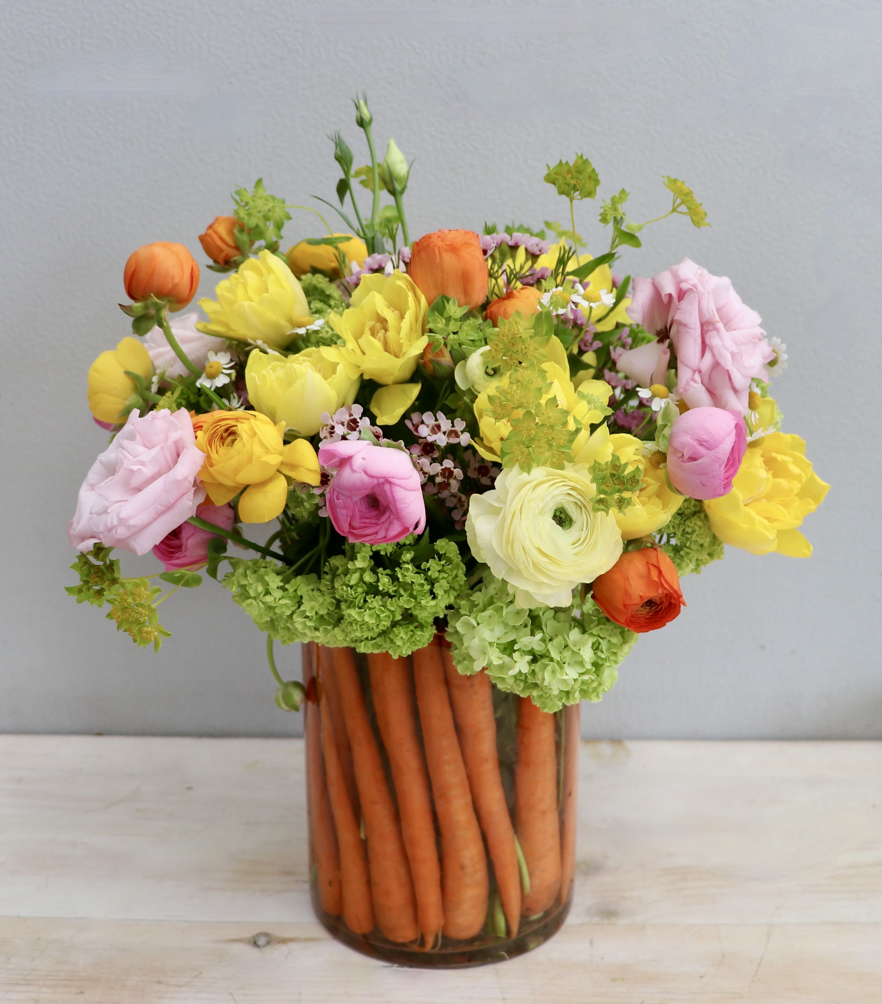 Carrot Patch Posies - My Glendale Florist  - Easter blooms are here! This arrangement makes for the perfect gift, we've paired together bright ranunculus, tulips, and lisianthus for a fun festive look. Don't forget to upgrade for more blooms! 