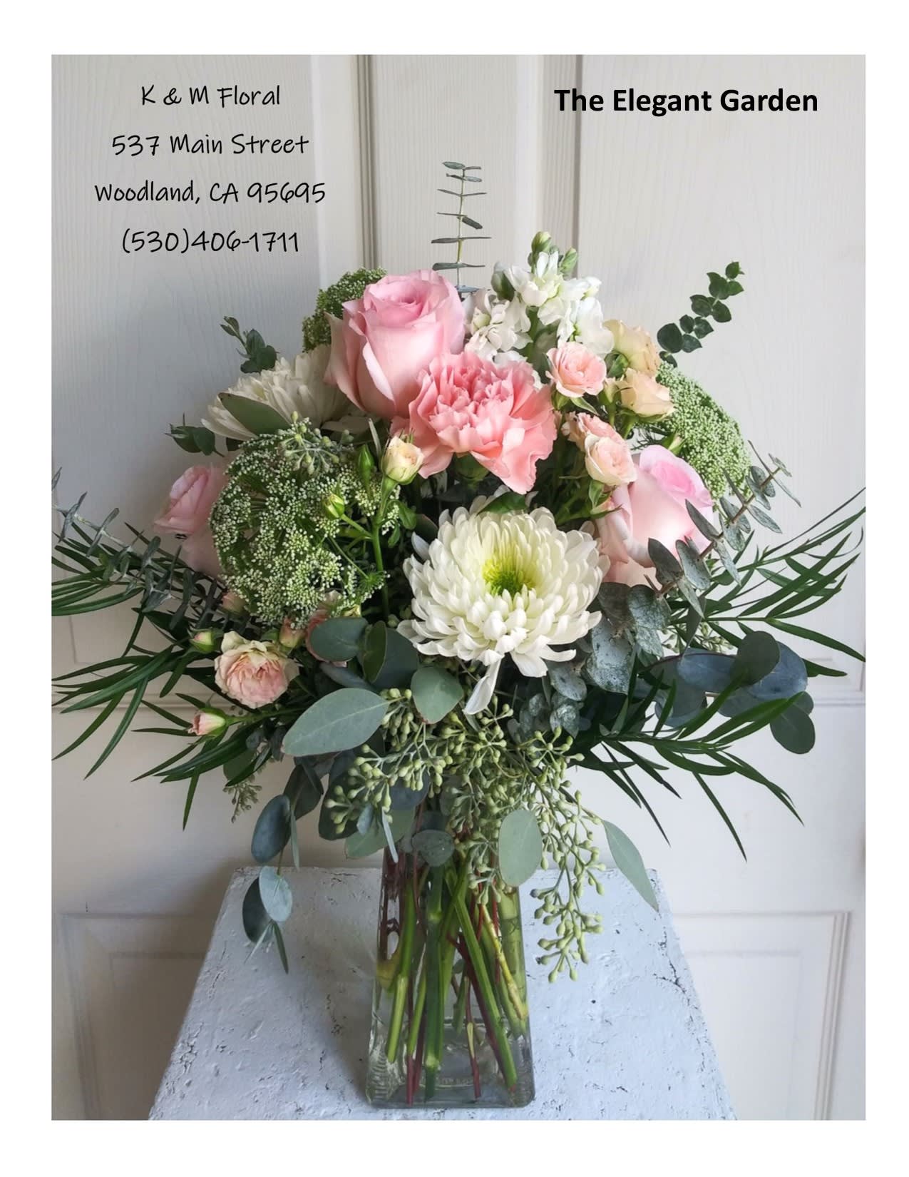 Elegant Garden - The Elegant Garden bouquet is soft and sweet with luscious greenery that gives this bouquet a one of a kind look. Roses, spray roses, chrysanthemums, stock and carnations in the white and soft pink tones in a clear glass vase. Vase is approx 8&quot; tall