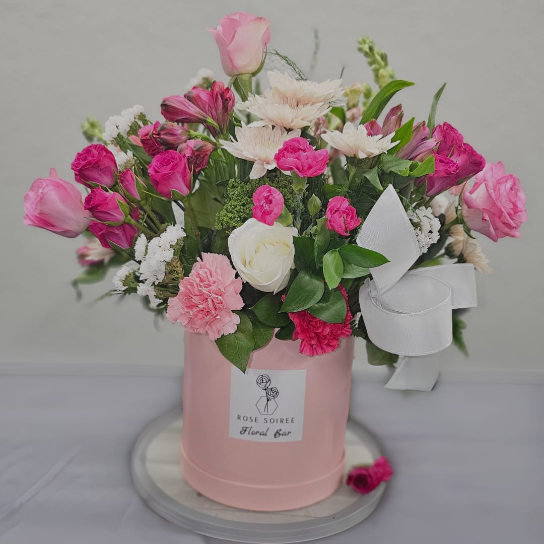 Pretty in Pink Garden Mix - Pretty in Pink hat box arrangement filled to the brim with vibrant flowers in lovely shades of pink and white with lush greenery! These are Designers Choice of in season and filler flowers , will include Pink Roses and assorted spray roses, alstromeria, mums, and carnations to name a few of the blooms that will arrive in your box! May also include exotic flowers like orchids, scabiosa, star of bethlehem and craspedia as available. 