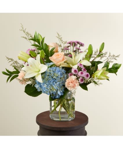 Beach House Bouquet - Take yourself on a seaside getaway with our Beach House bouquet. The calming blue hydrangea is the perfect summer pair for the peach carnations and roses. Enjoy the fun lavender button pompons as a colorful contrast to the classic blooms.