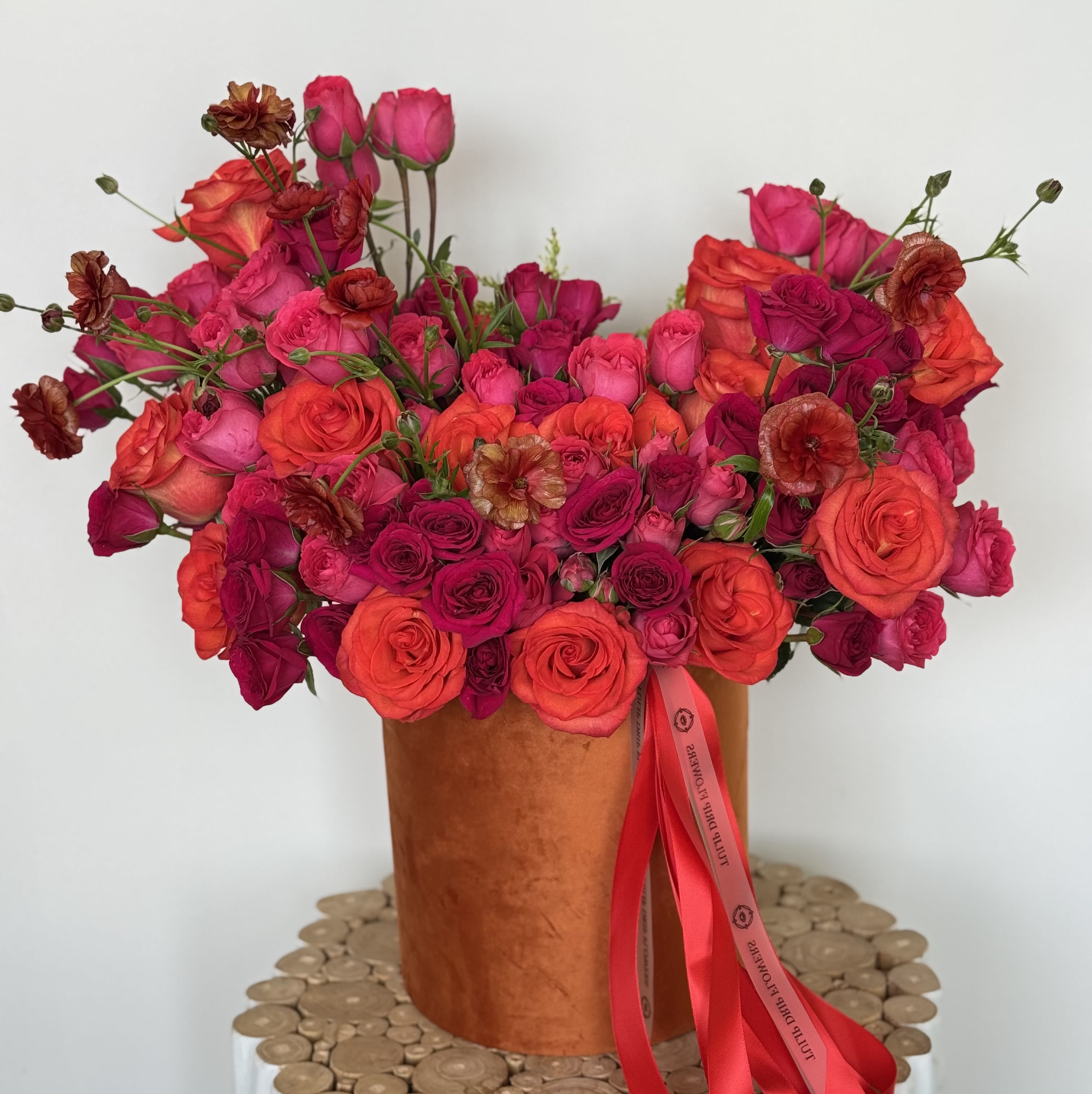 Vibrant Rose Fusion  - Make a bold statement with this fiery mix of red, hot pink, and orange roses, accented with deep burgundy florals. Arranged in a burnt orange velvet box, it’s the ultimate Mother’s Day flower arrangement with impact. We can add your Mother’s gift in any of our arrangements.  