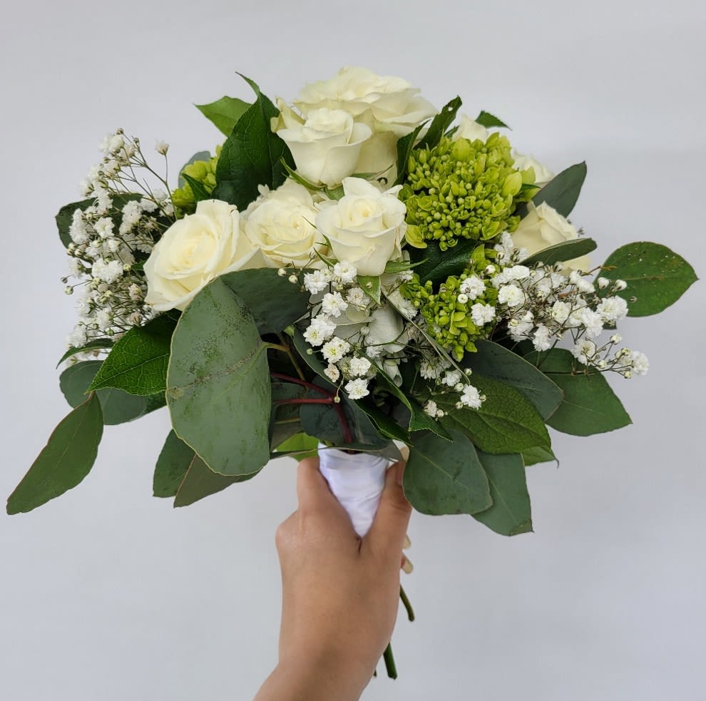 Nosegay in Greens and Whites - A Timeless Blend of Elegance and Natural Beauty Celebrate life’s most cherished moments with our Nosegay in Greens and Whites, a hand-held bouquet that exudes sophistication and grace. Perfect for weddings, recitals, proms, and homecoming dances, this bouquet is a versatile and stunning addition to any special occasion. ***Luxurious Composition: Featuring a lush base of white hydrangea, mini green hydrangeas, open premium roses, and tiny spray roses, this arrangement is accented with delicate filler flowers and lush greenery, creating a harmonious blend of texture and depth. ***Delicate Details: Natural greenery and soft floral accents add an organic touch, making this bouquet feel both refined and nature-inspired. ***Versatile Elegance: Bound in elegant white ribbon, this bouquet complements both semi-formal and formal attire, from bridal gowns to evening wear. Each bouquet is meticulously hand-designed to ensure freshness and quality, making it the perfect choice for creating unforgettable memories.