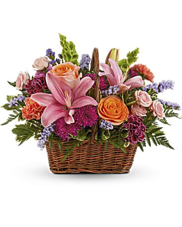 Blooming Joy Bouquet  - Like an island sunrise, this basket of orange and pink blooms are a glowing reminder of life's greatest joys. This bouquet features orange roses, light pink spray roses, pink asiatic lilies, burgundy carnations, orange carnations, bells of Ireland, purple cushion spray chrysanthemums, blue sinuata statice, variegated pittosporum and leatherleaf fern. Delivered in a Basket with Handle. 